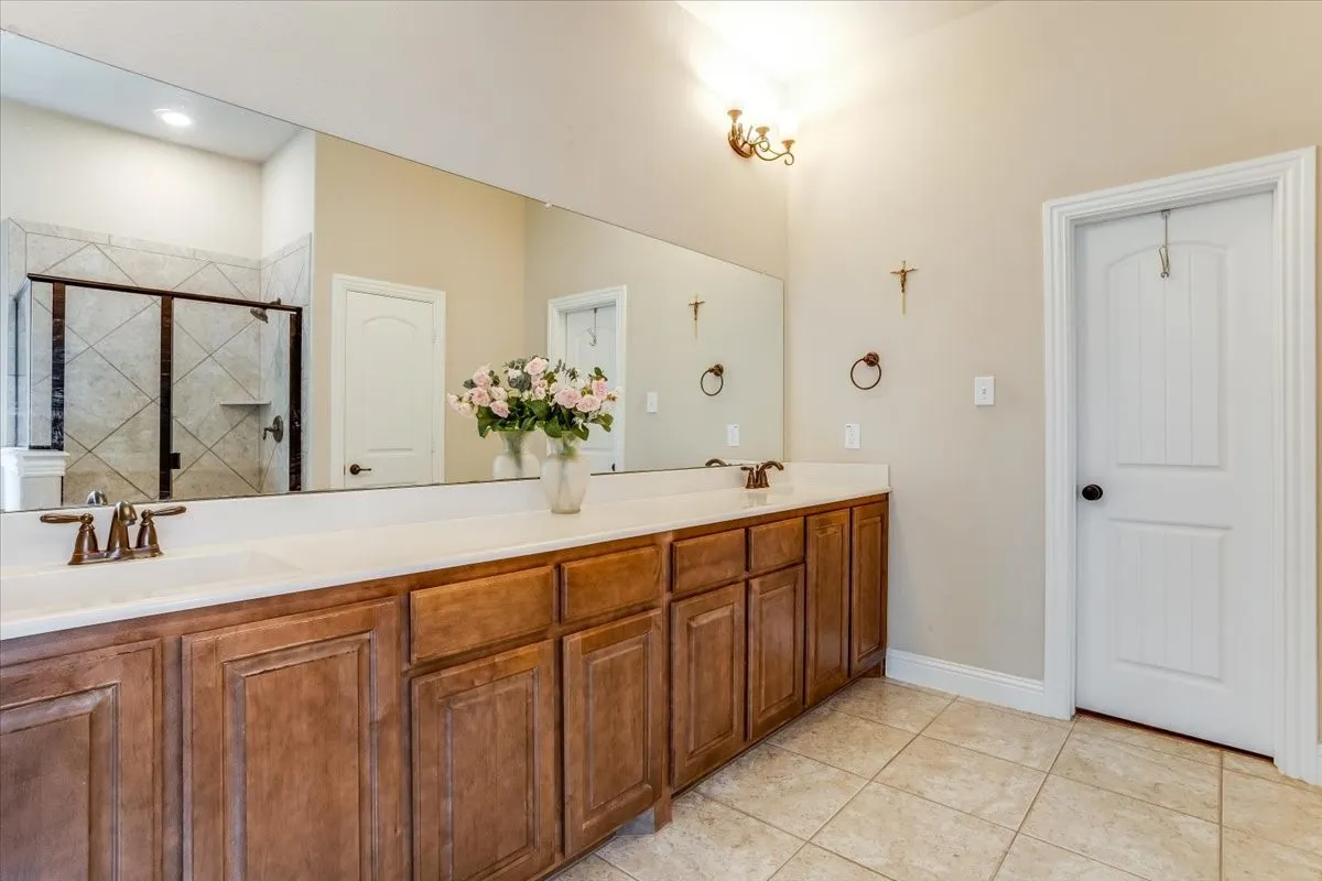 Dual vanity with integrated sinks, wood-finish cabinetry, and a large mirror