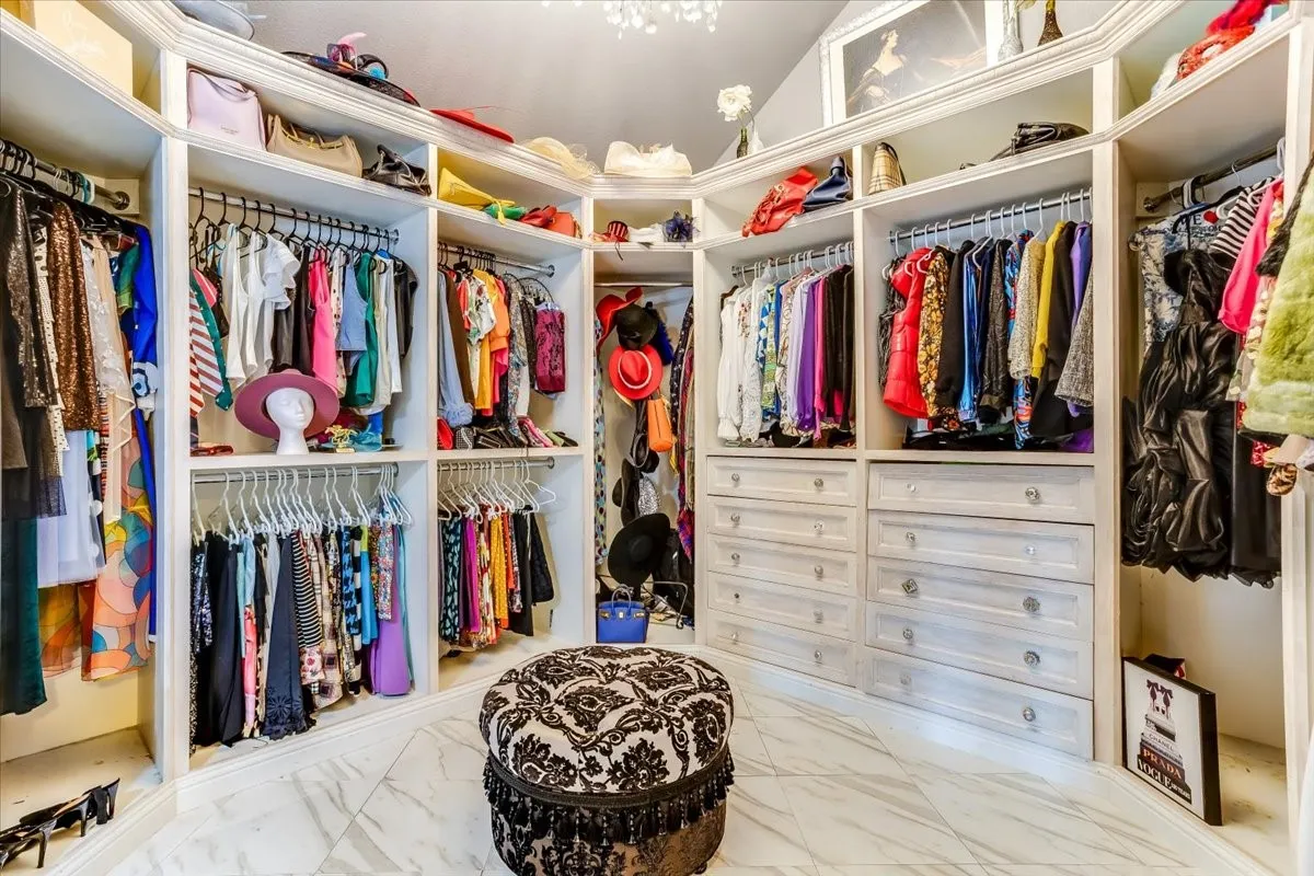 Expansive walk-in closet featuring white built-in cabinetry and shelving