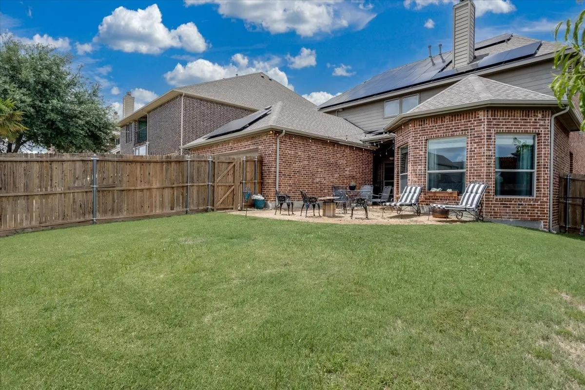 Expansive backyard featuring a spacious lawn, wood privacy fencing, and a brick exterior with multiple windows