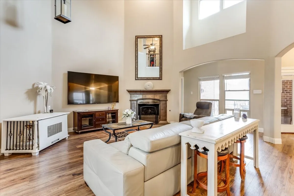 Two-story living area featuring wood-finish flooring and a fireplace with a stone surround