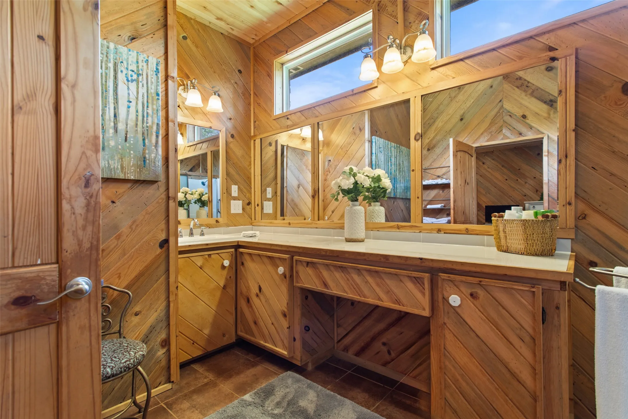 Bathroom featuring extensive wood paneling, dual vanity with undermount sinks, and a built-in makeup counter