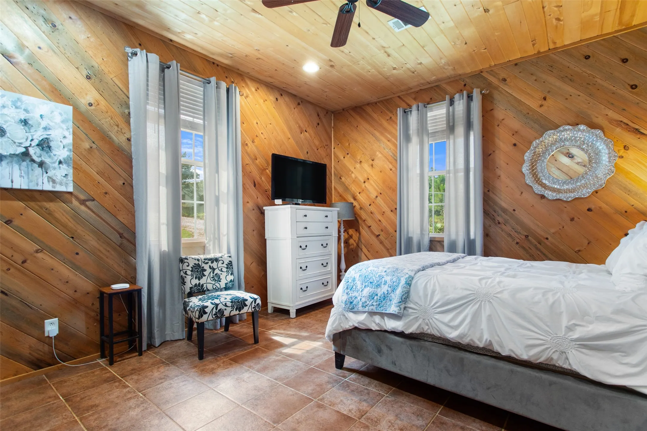 Interior space featuring diagonal wood-paneled walls and ceiling, tiled flooring, and a ceiling fan