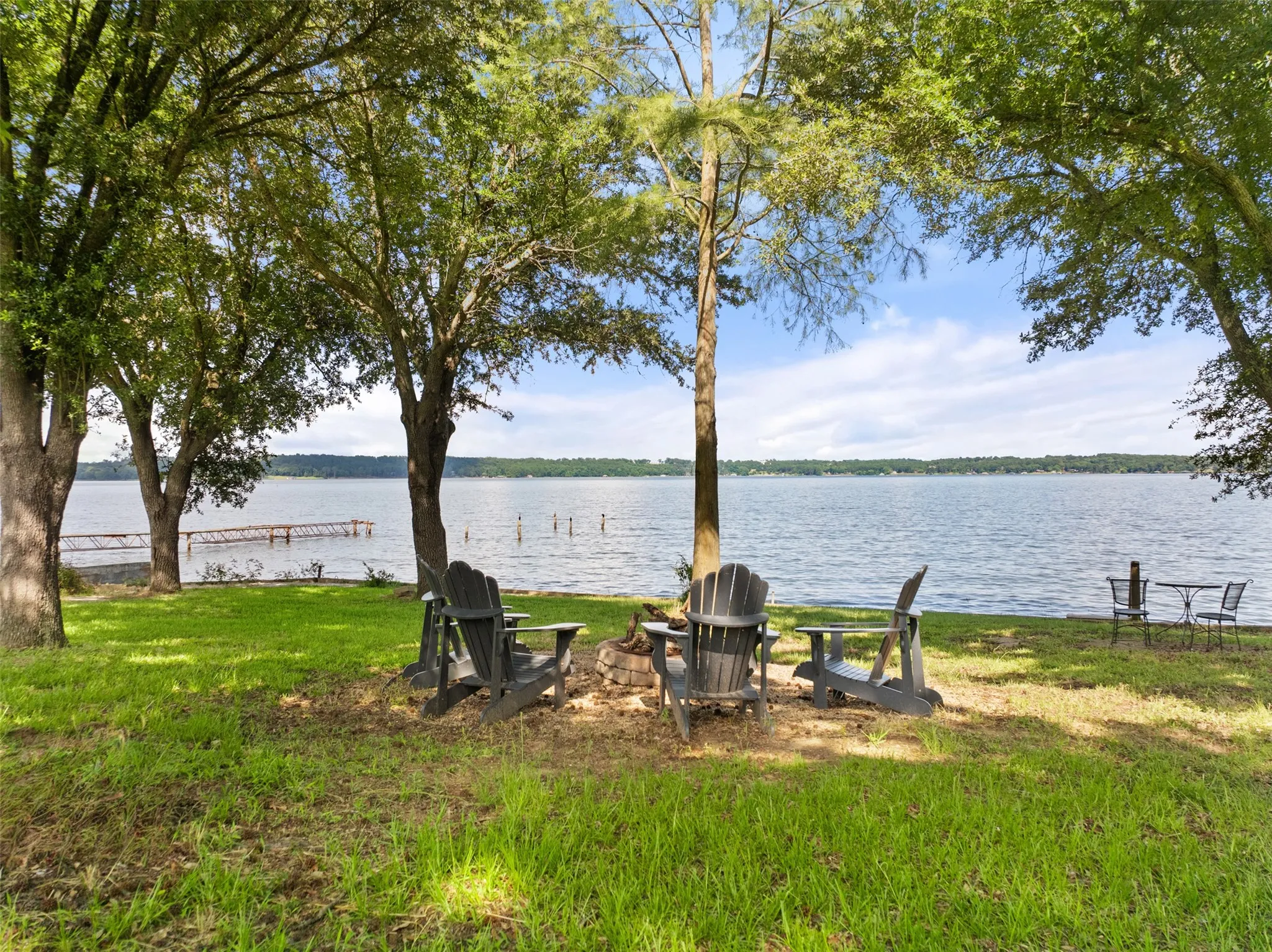 Expansive waterfront lawn featuring mature trees and a tranquil lake backdrop