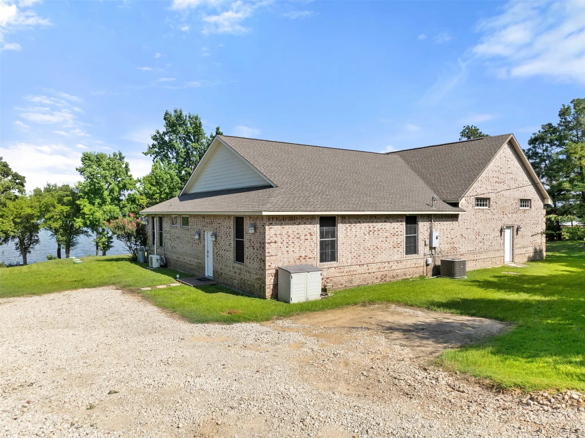 Brick exterior with a multi-pitch roofline, multiple access doors, and a gravel drive