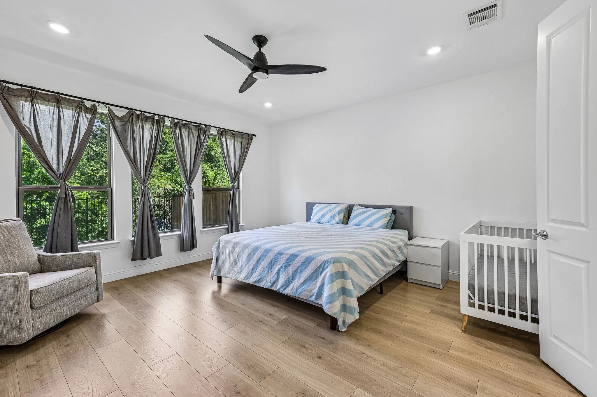 Bedroom featuring wood-finish flooring, white walls, and a contemporary ceiling fan