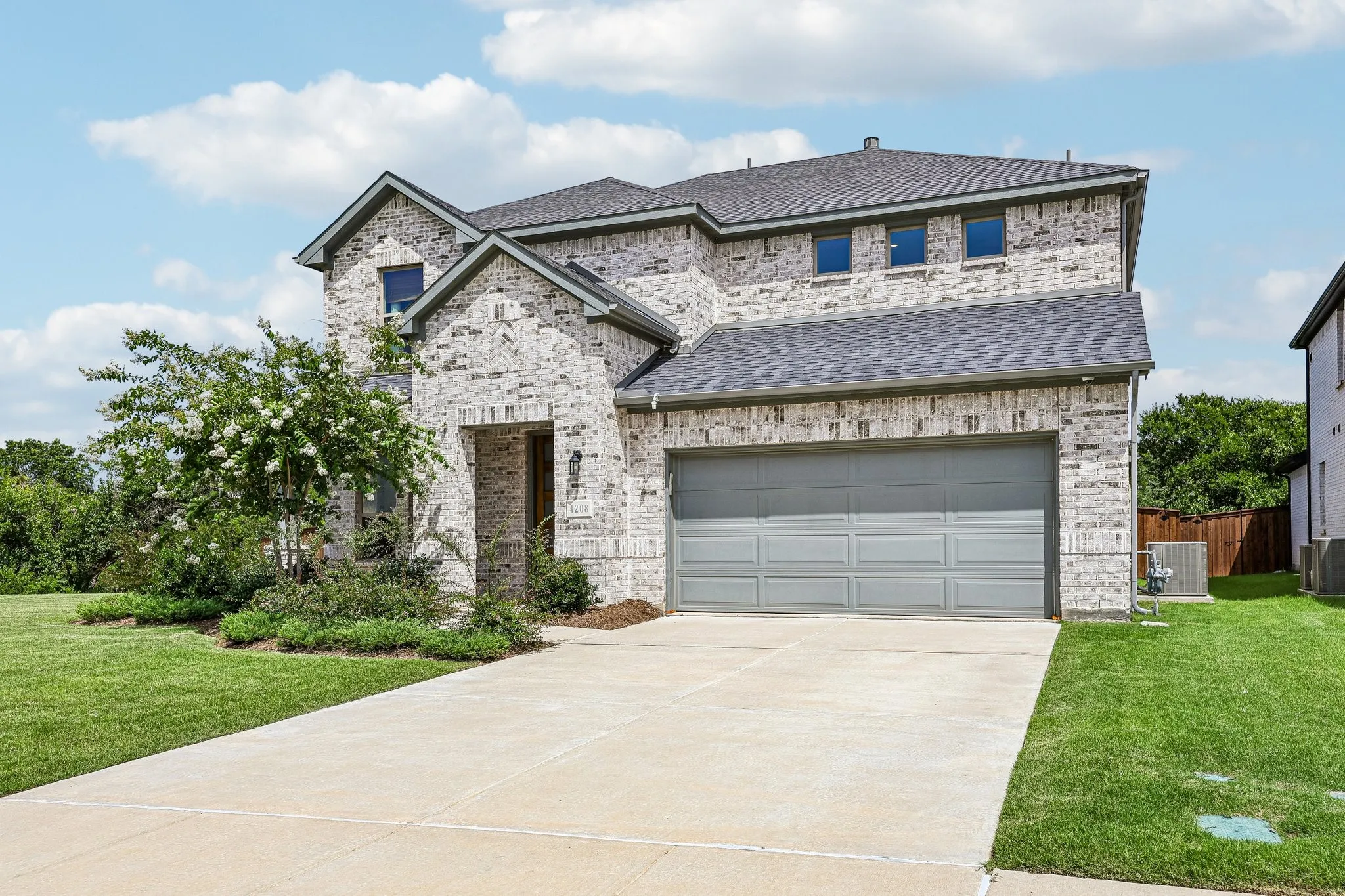 Gray brick exterior with dark gray roofing and a two-car garage
