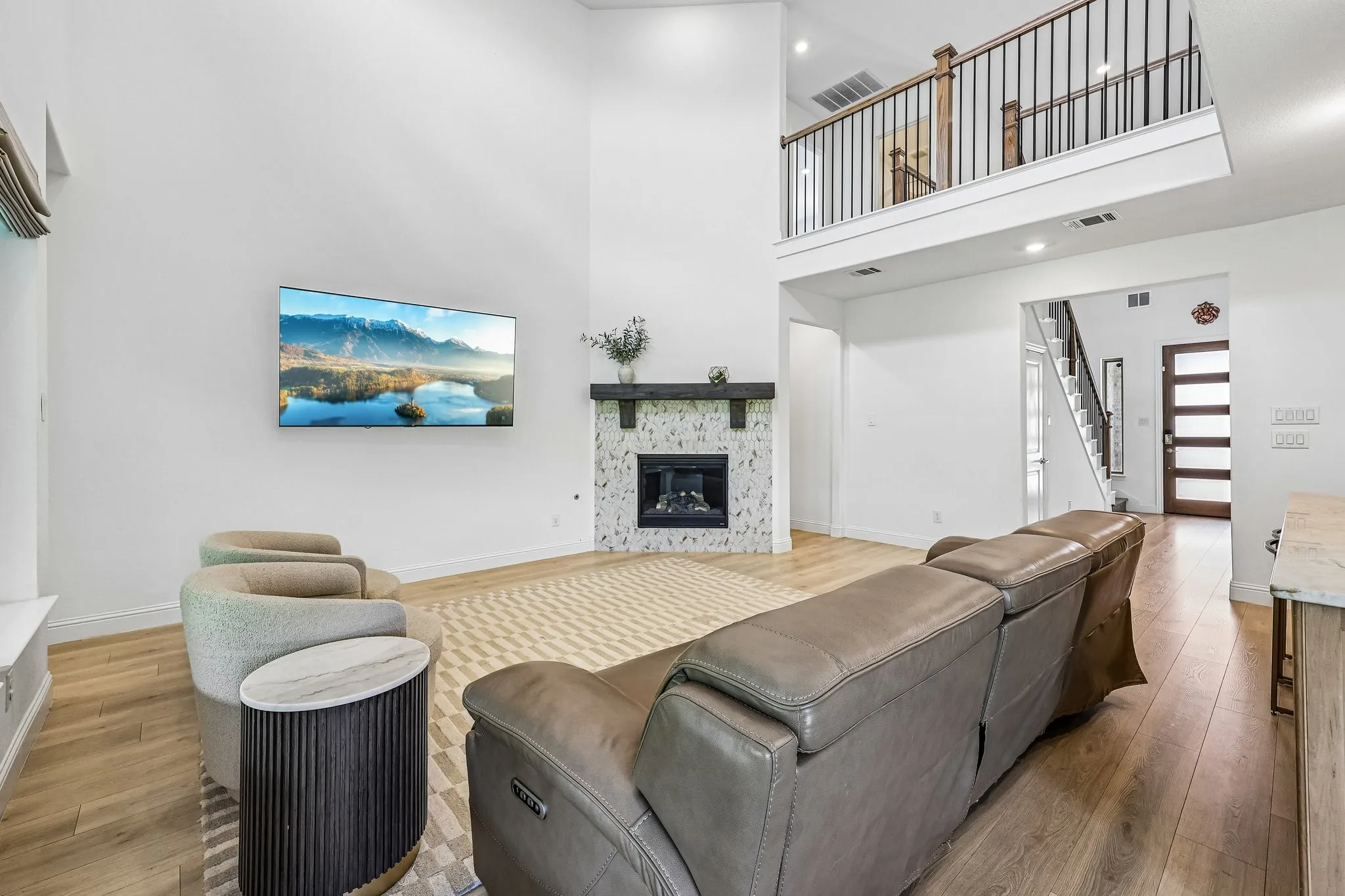 Vaulted living area featuring a fireplace with a white tile surround and dark wood mantel