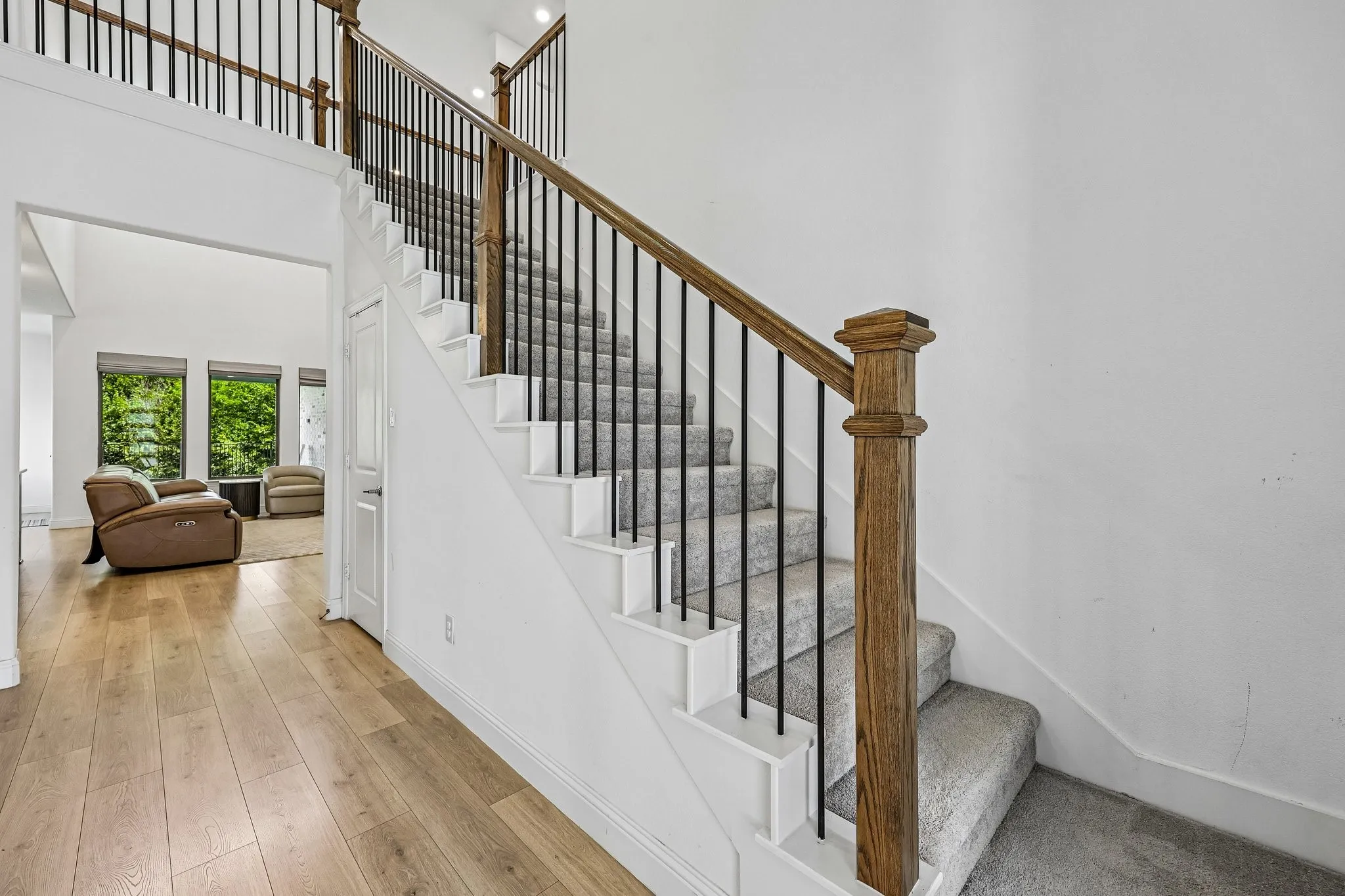Grand staircase featuring wood railings with black balusters and light gray carpeted steps