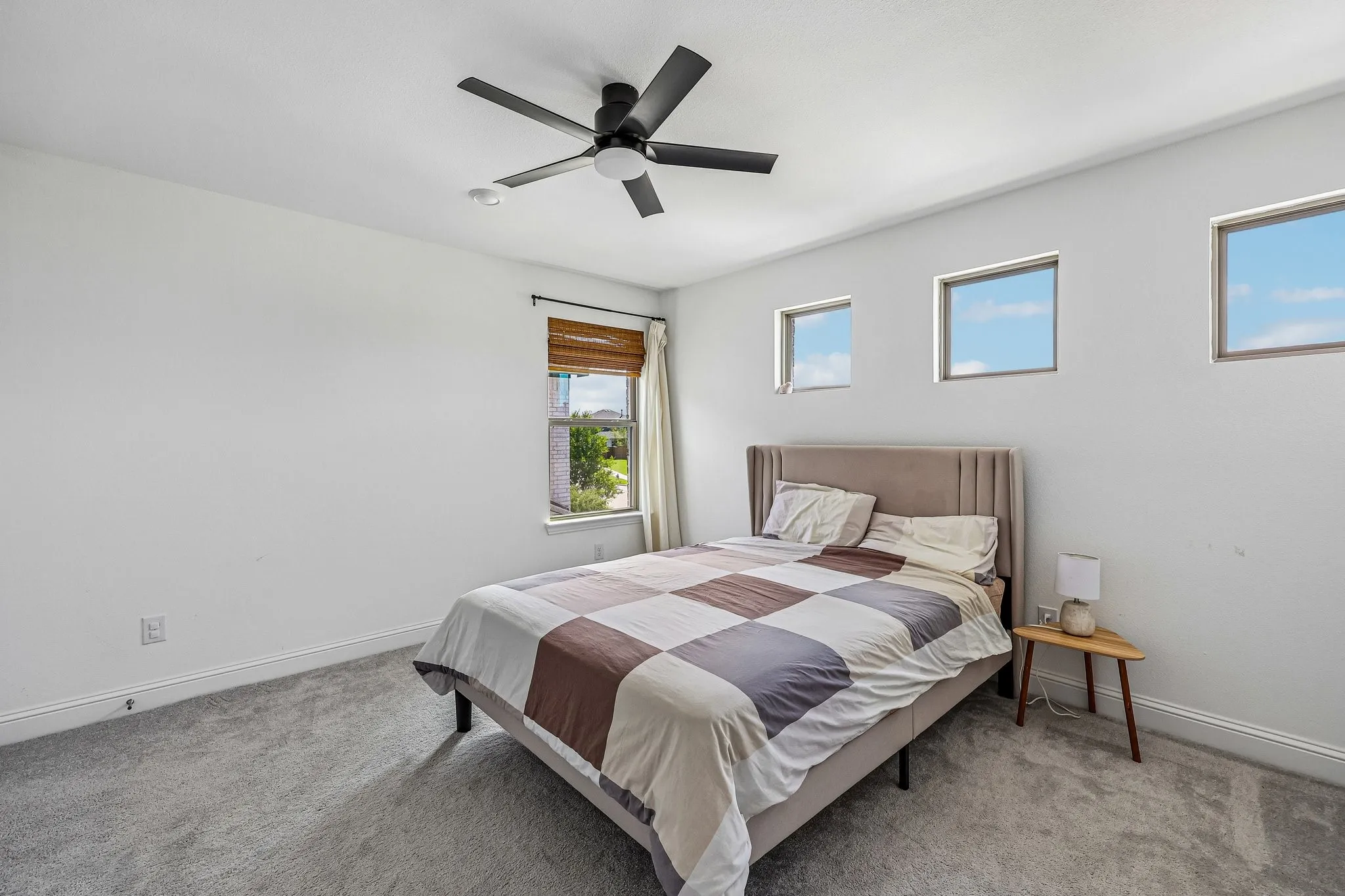 Carpeted bedroom featuring multiple windows, a ceiling fan with integrated lighting, and white baseboards