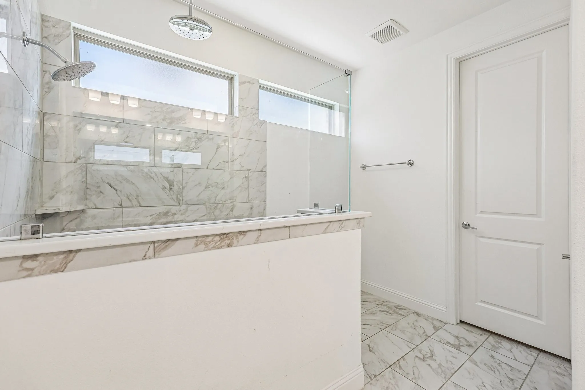 Shower enclosure featuring a rain shower head, handheld shower fixture, and built-in shelving