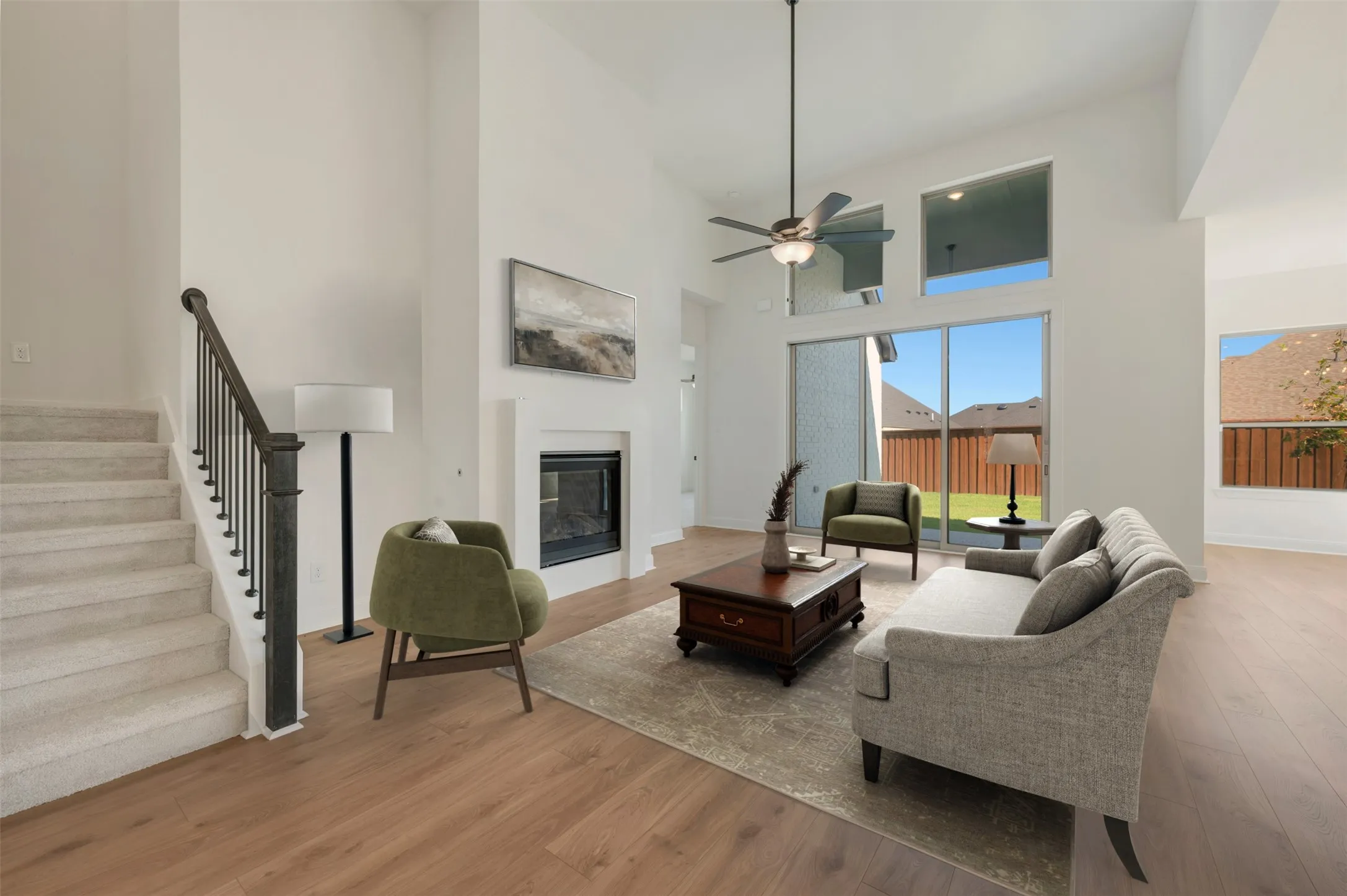 Vaulted ceilings, a fireplace, wood-finish flooring, a ceiling fan, and large windows