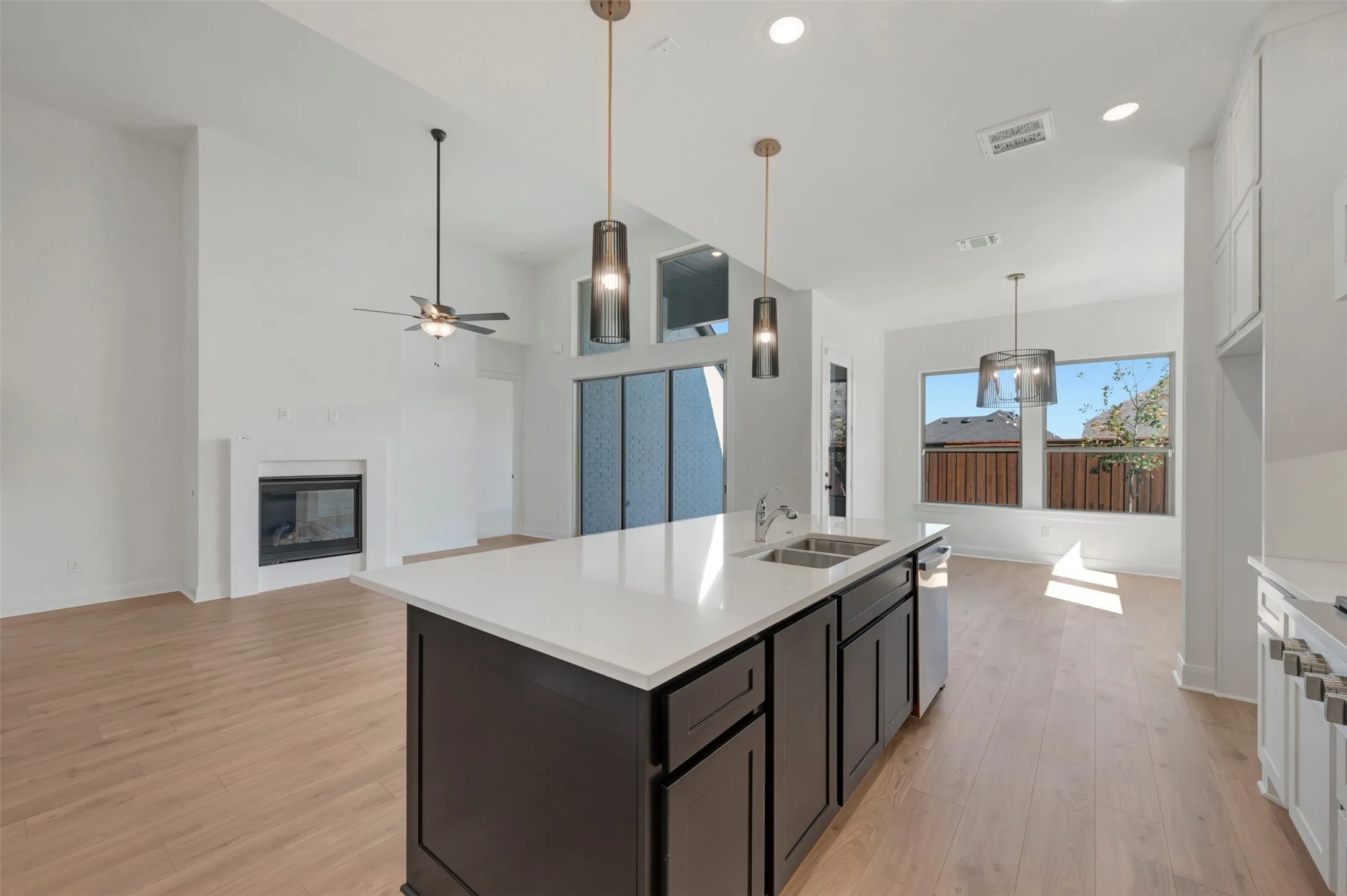 White kitchen island with a double basin sink, quartz countertop, and pendant lighting