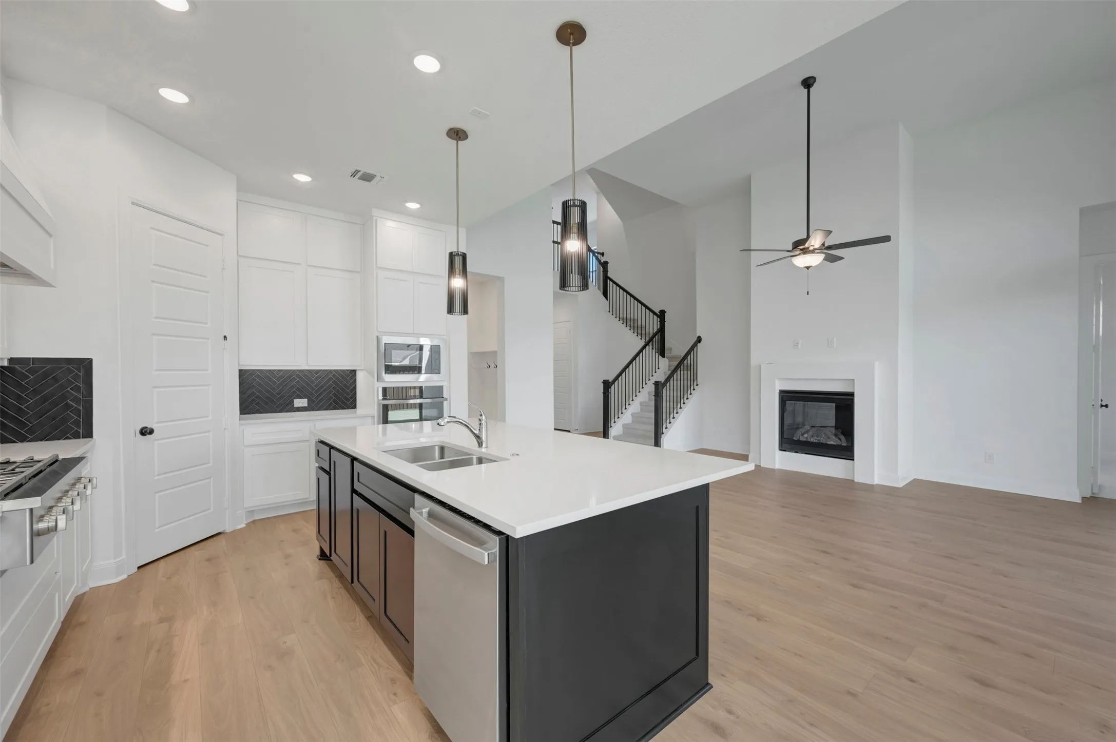 Open-concept kitchen featuring white cabinetry, a large kitchen island with a built-in sink, and stainless steel appliances