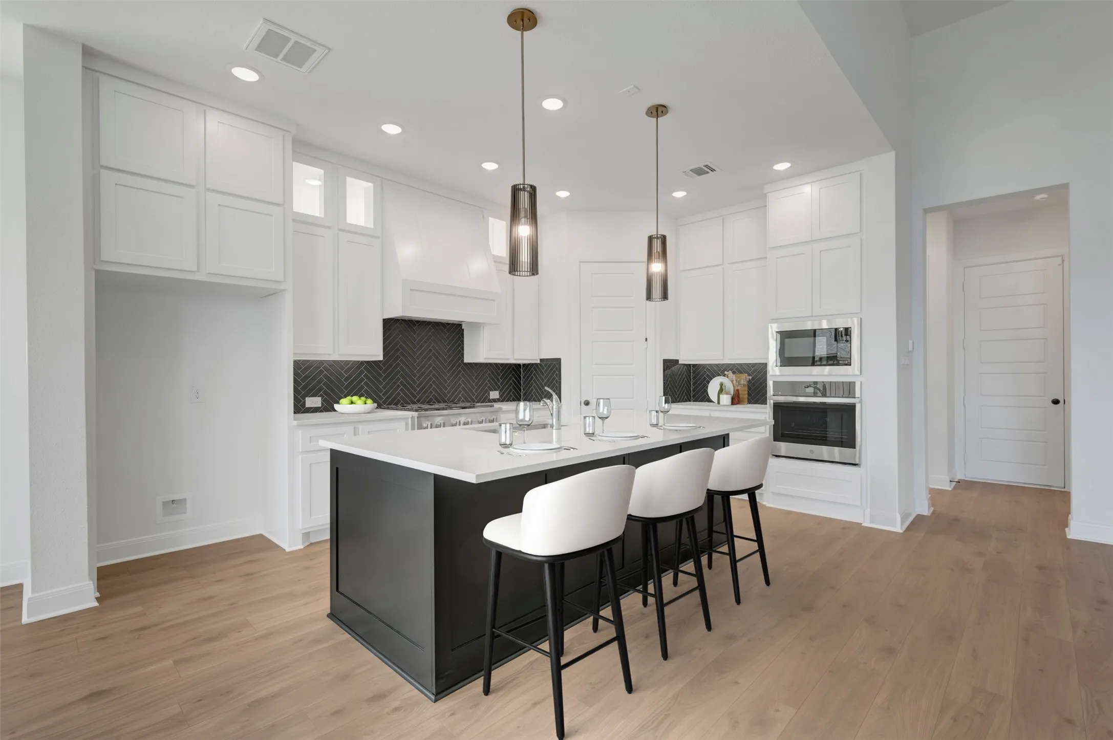 Modern kitchen with a dark-finish island, light-toned wood-finish flooring, white cabinetry, and recessed lighting