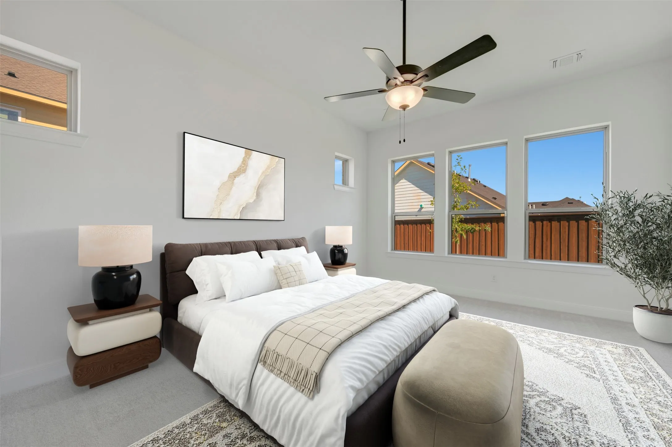 Vaulted ceiling with an attached ceiling fan, three large windows, light gray wall paint, and gray carpet flooring