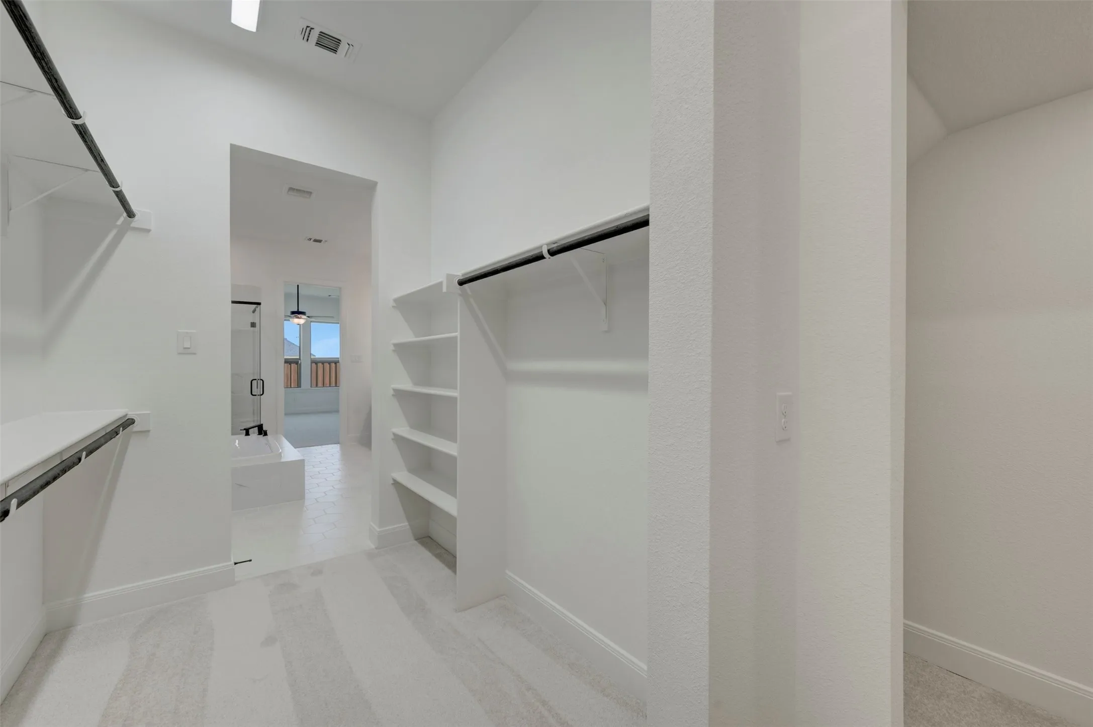 Spacious walk-in closet with carpet flooring, multiple shelving units, and hanging rods