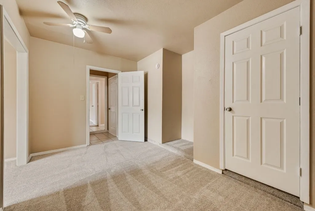 Neutral-toned room featuring light beige walls and a textured carpeted floor