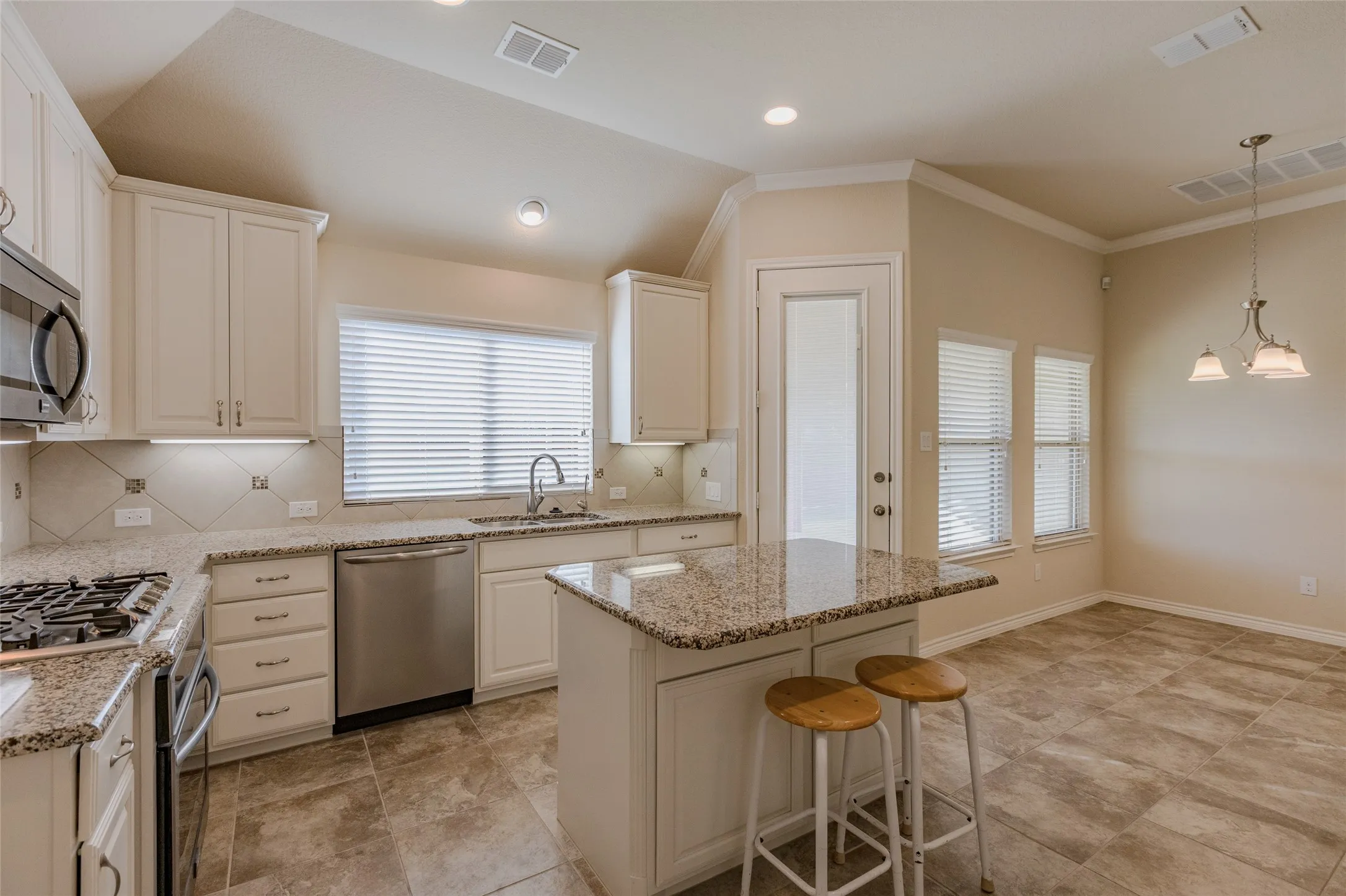 Modern kitchen featuring light-toned cabinetry, granite countertops, stainless steel appliances, and tile flooring