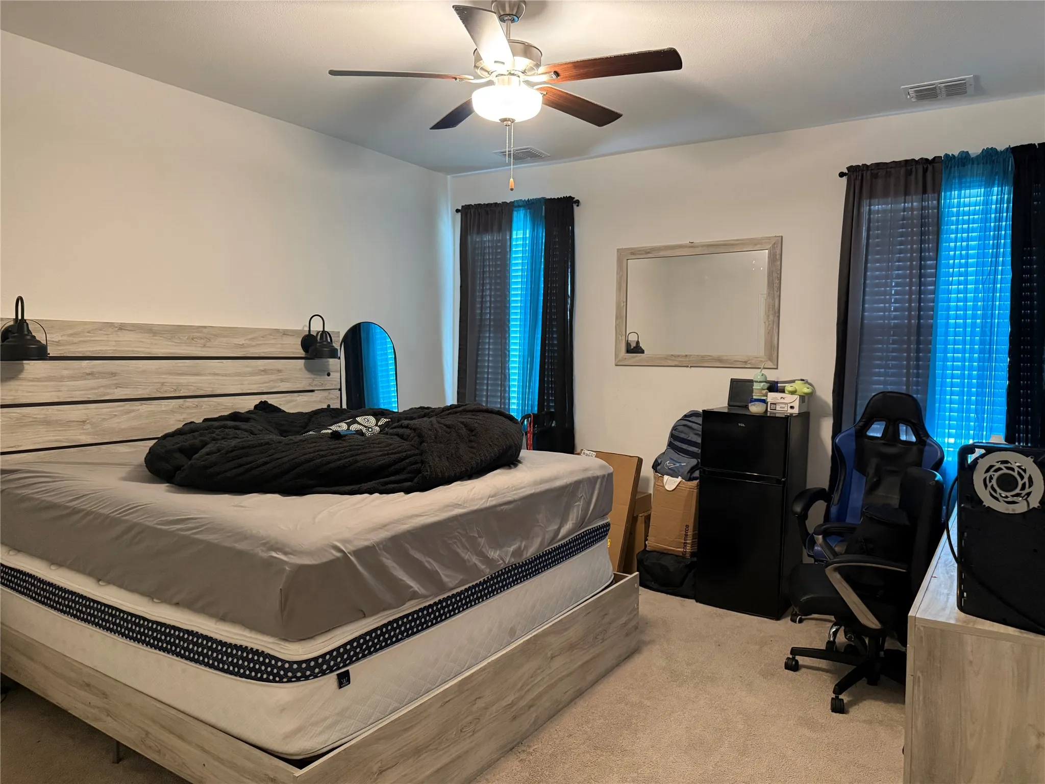 Spacious room featuring neutral carpeting, a ceiling fan with integrated lighting, and dual windows