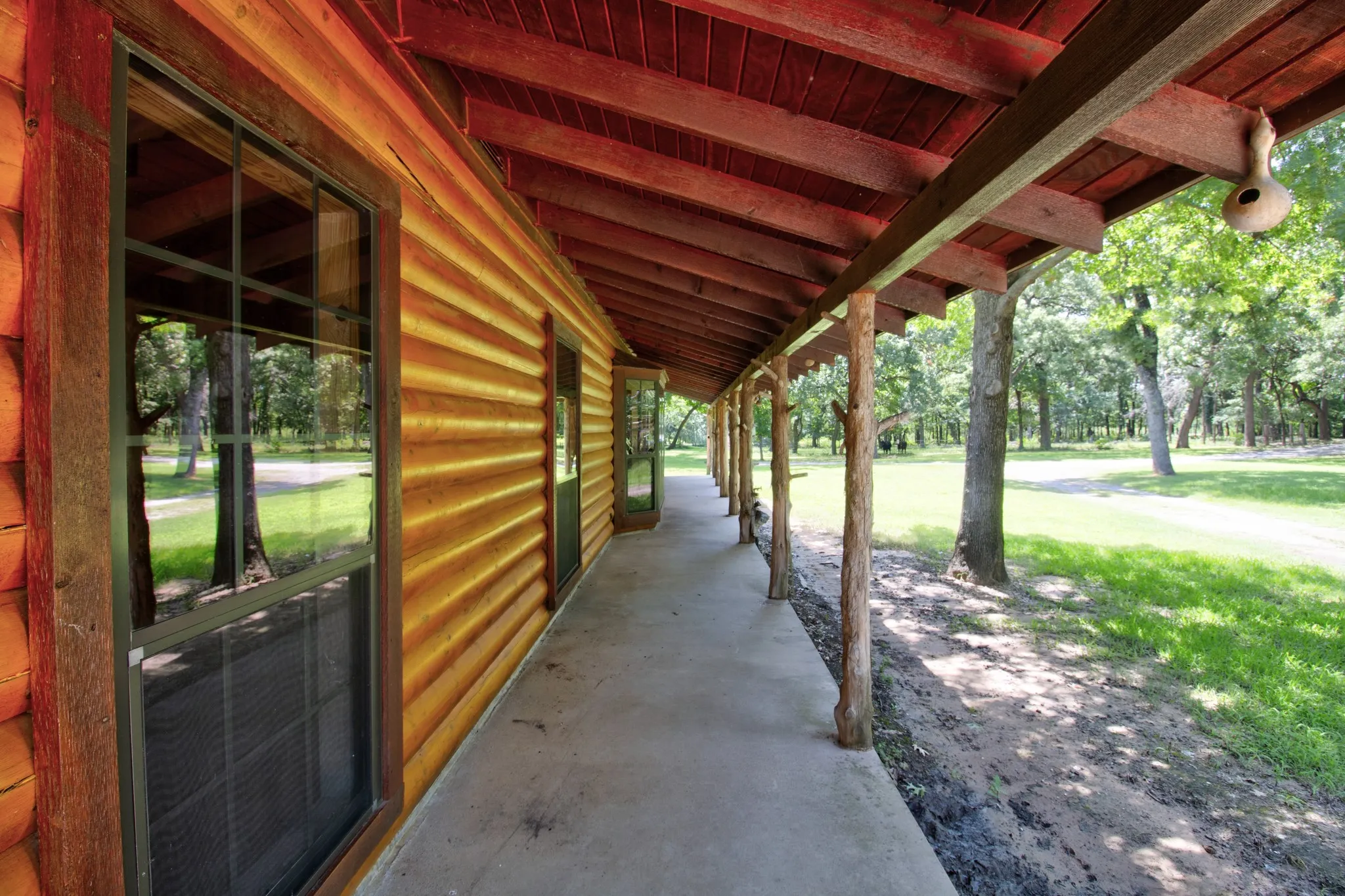 A deep, shaded concrete porch extends along the length of the home, providing the perfect shaded spot to sit back and enjoy the peaceful acreage views.
