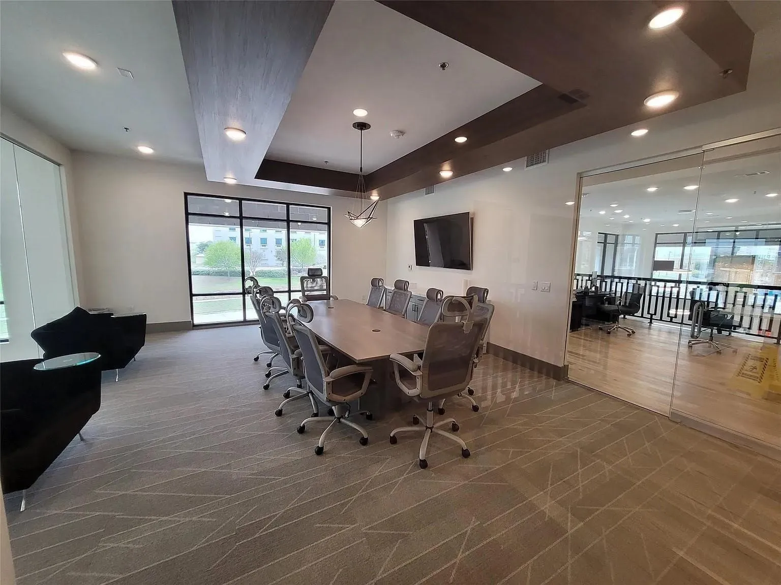 Conference room featuring a large table with seating for ten, recessed lighting, and a prominent wall-mounted display