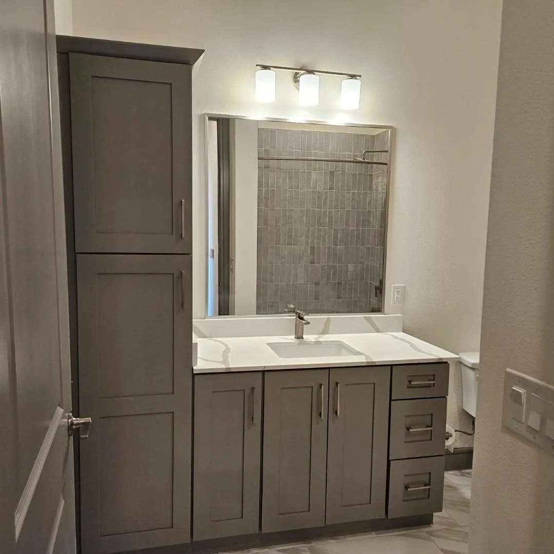 Bathroom vanity featuring a light-colored countertop with an integrated sink, brushed nickel faucet, and a large mirror