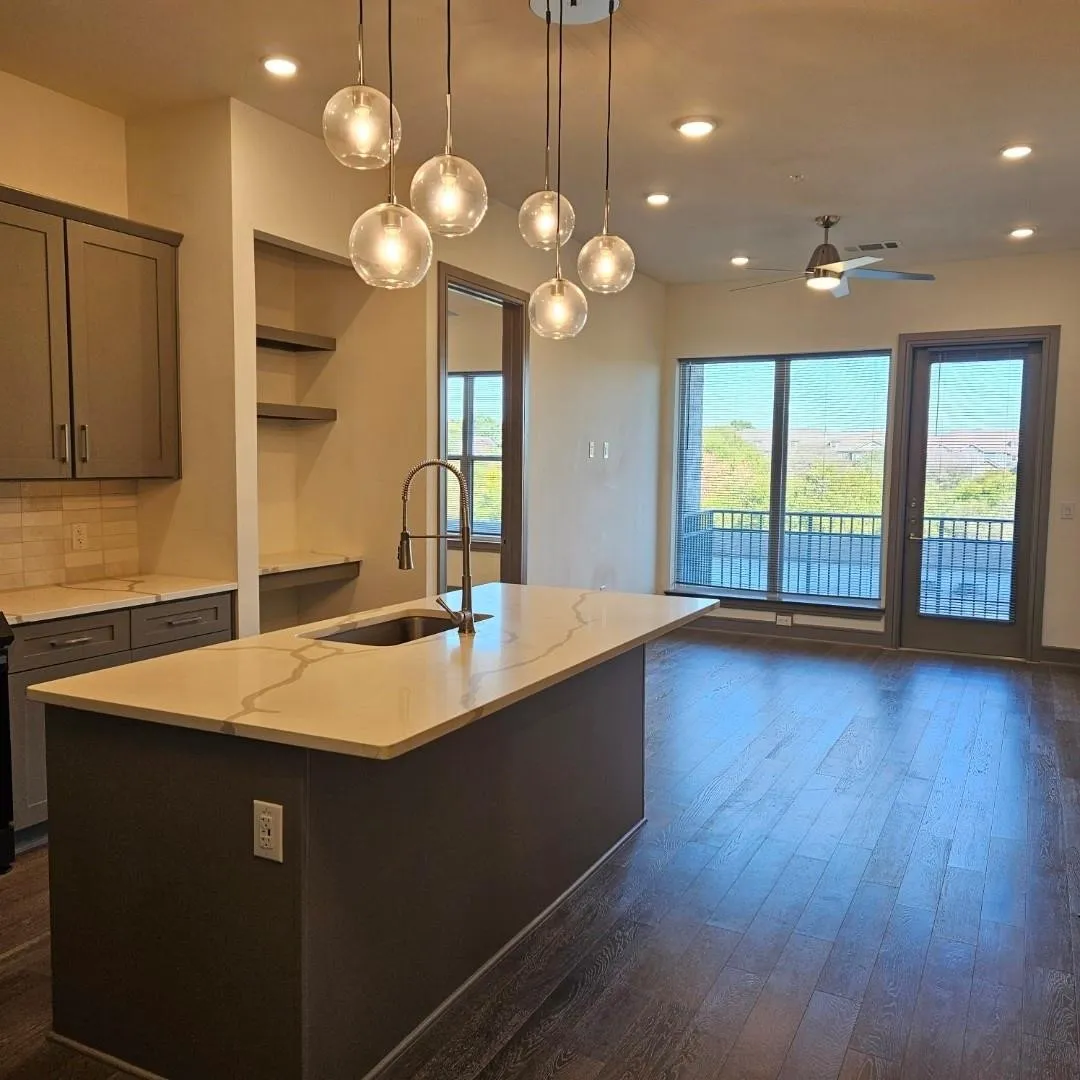 Central kitchen island with a light-toned countertop, undermount sink, and gooseneck faucet