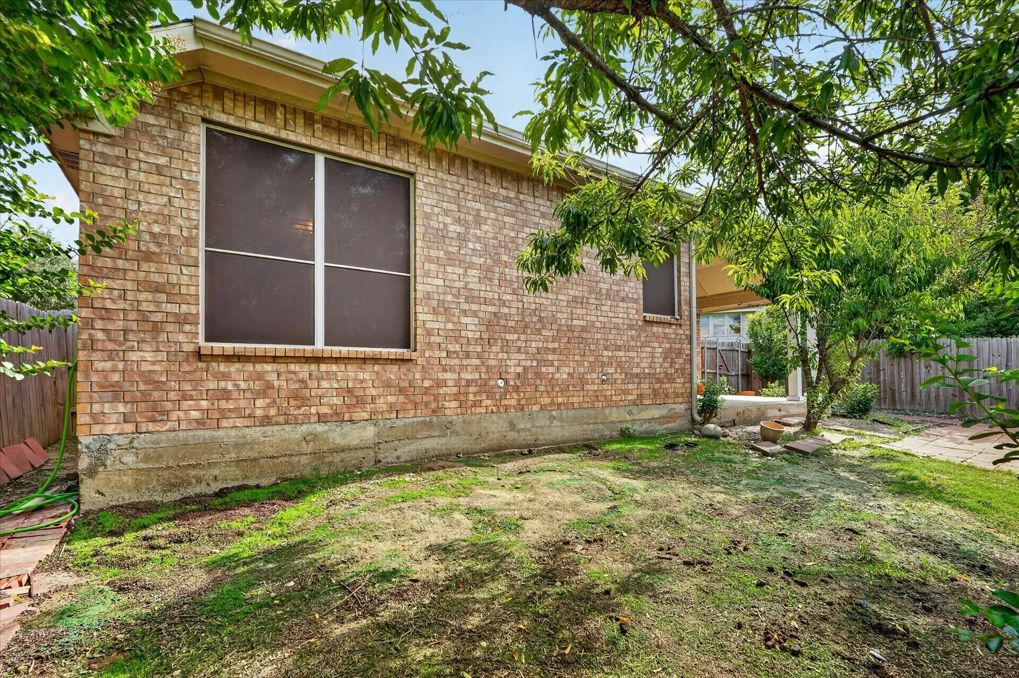 Brick exterior with a large window and a covered patio area