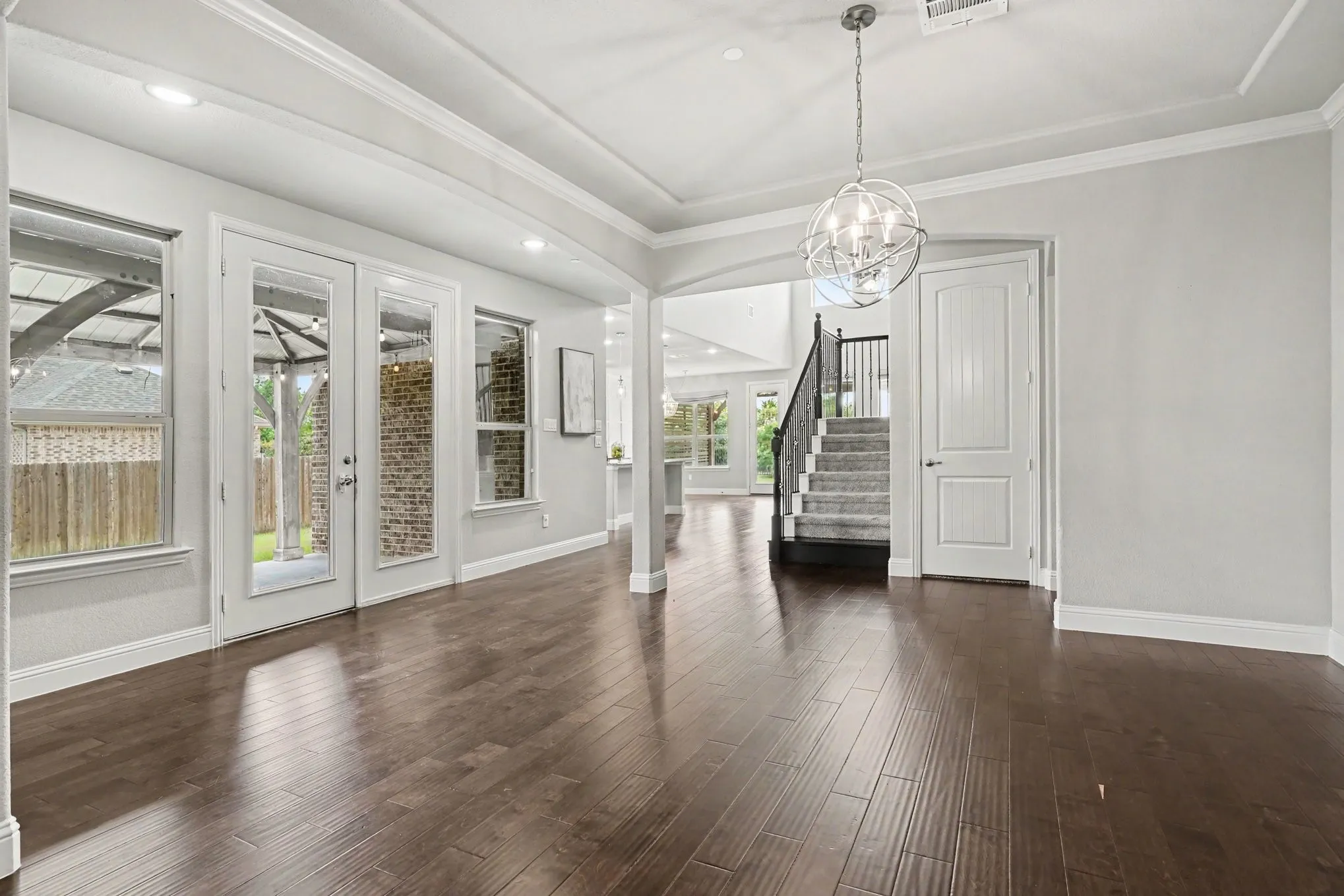 Dining area featuring a tray ceiling with a contemporary chandelier, wood-finish flooring, and arched architectural details
