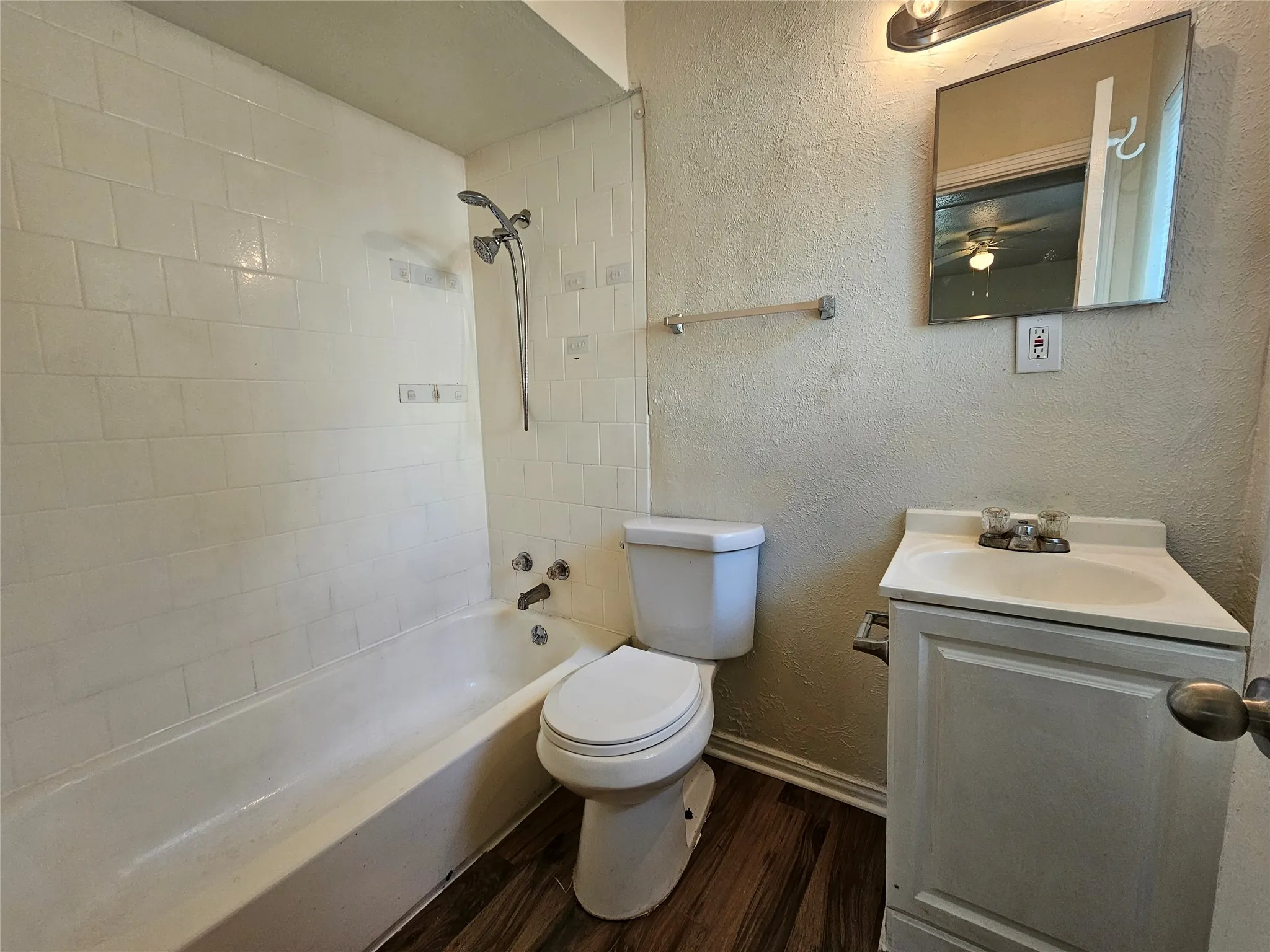 Bathroom featuring a white subway tile shower surround and a tub with a handheld showerhead