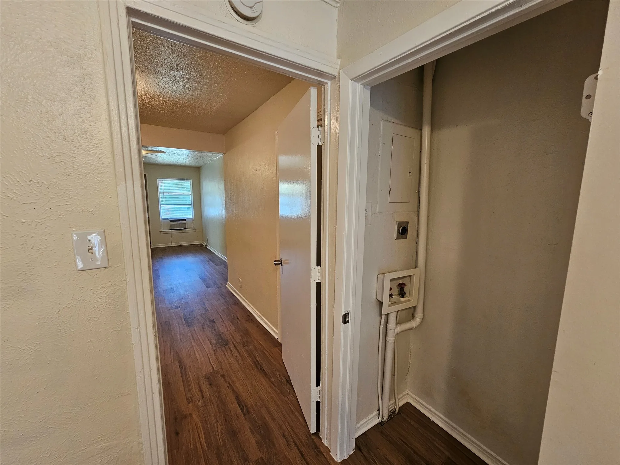 Interior hallway with wood-finish flooring, light-colored walls, and white trim