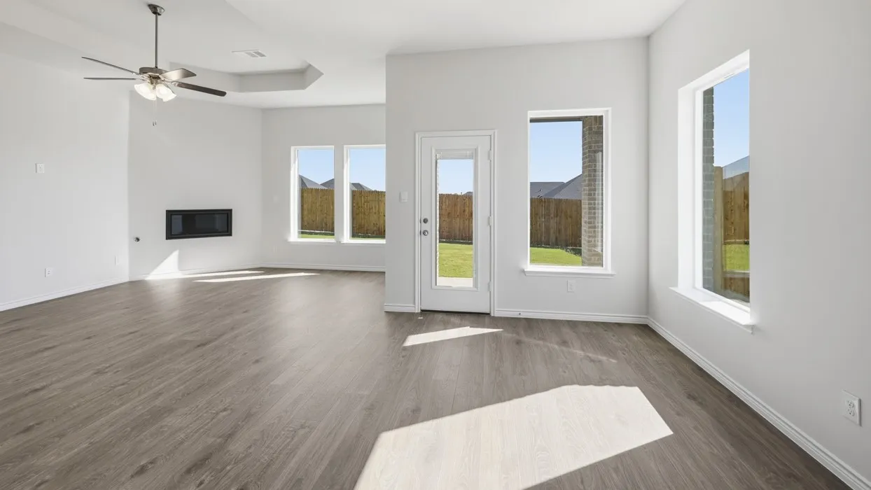 Spacious interior with wood-finish flooring, multiple windows, a ceiling fan, and a built-in electric fireplace