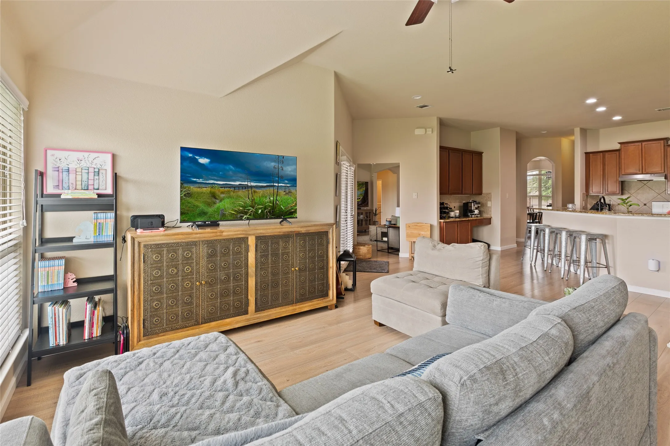 Expansive living space featuring wood-finish flooring, vaulted ceilings, and a ceiling fan