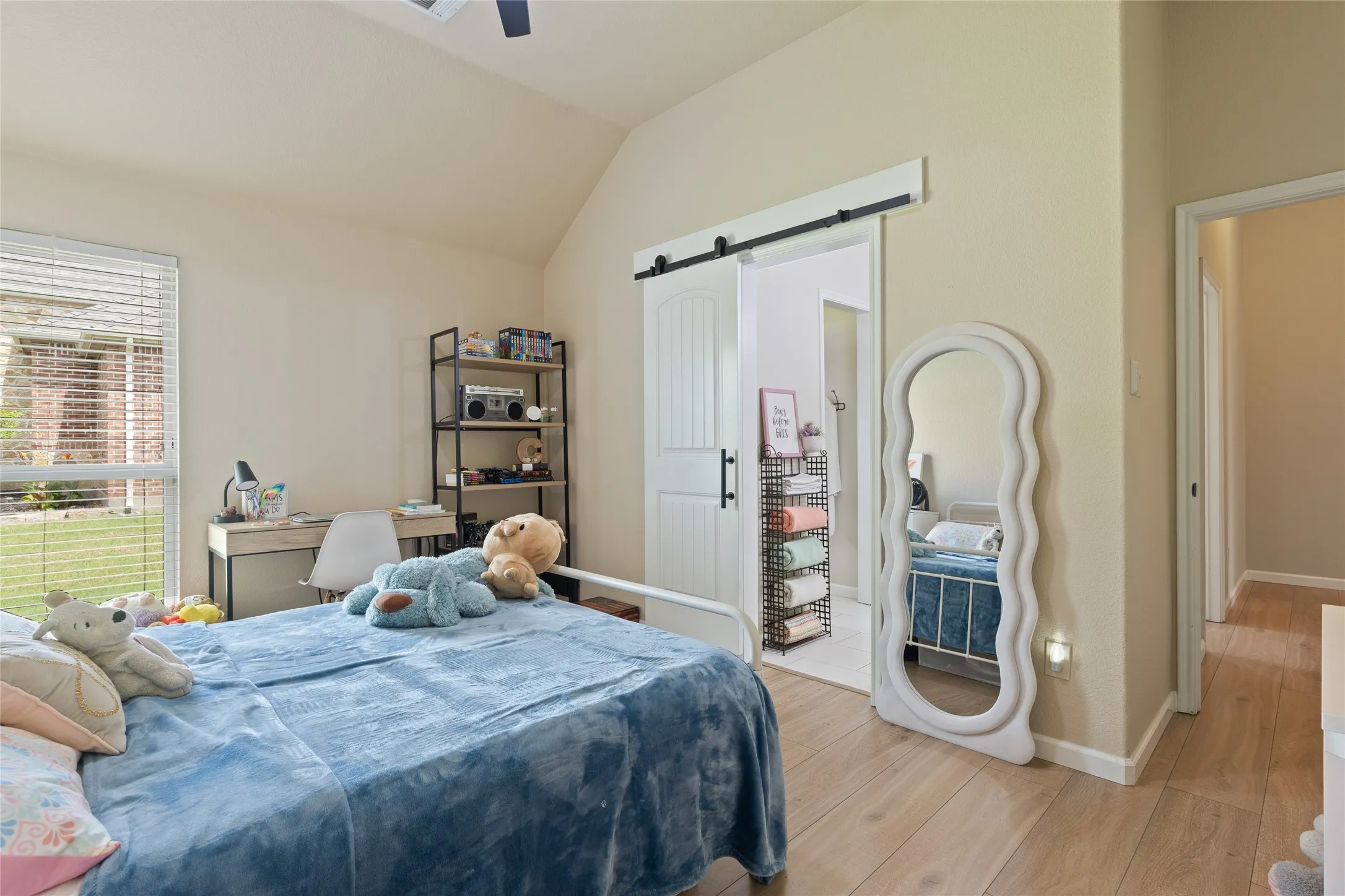 Vaulted ceiling bedroom featuring wood-finish flooring and a white barn door