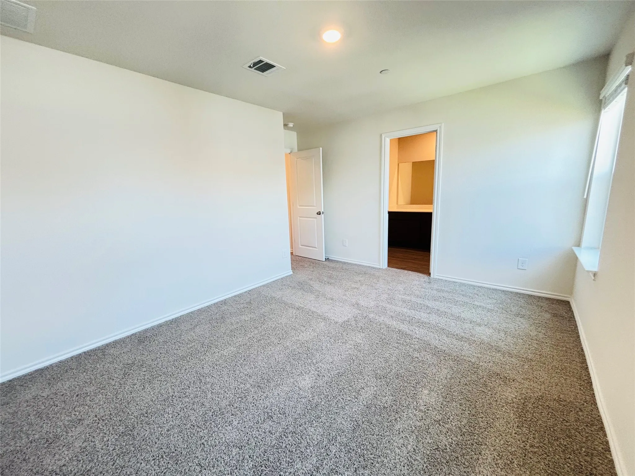 Spacious interior featuring neutral carpeting, white wall finishes, and a window with a deep sill