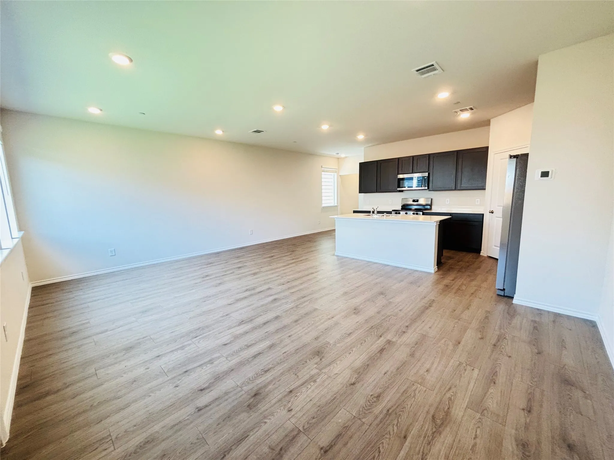 Open-concept living space featuring wood-finish flooring, recessed lighting, and a white kitchen island