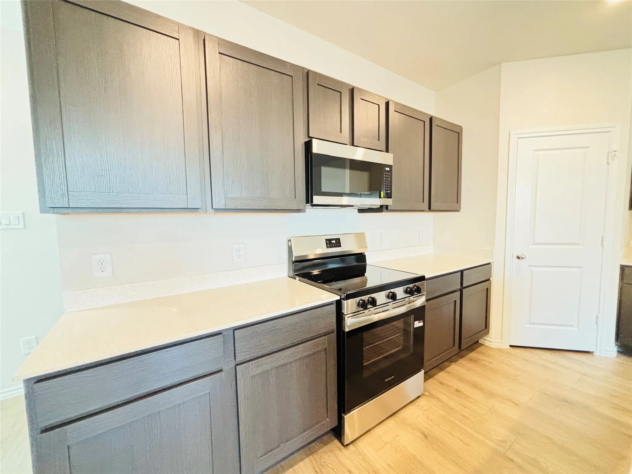 Kitchen featuring a stainless steel range, coordinating microwave, and light wood-finish flooring