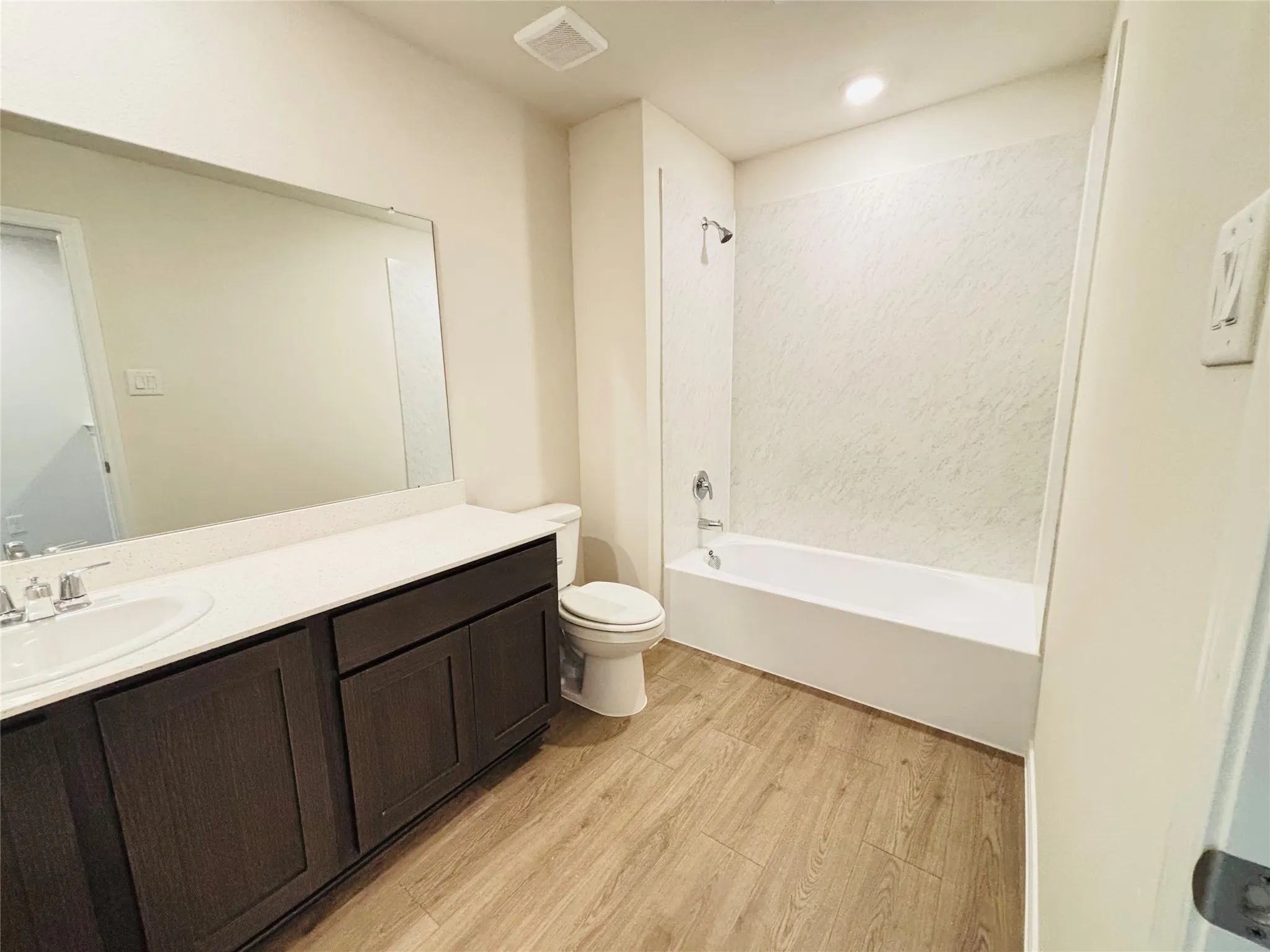 Full bathroom featuring a single vanity with wood-finish cabinetry, a white countertop, and an integrated sink