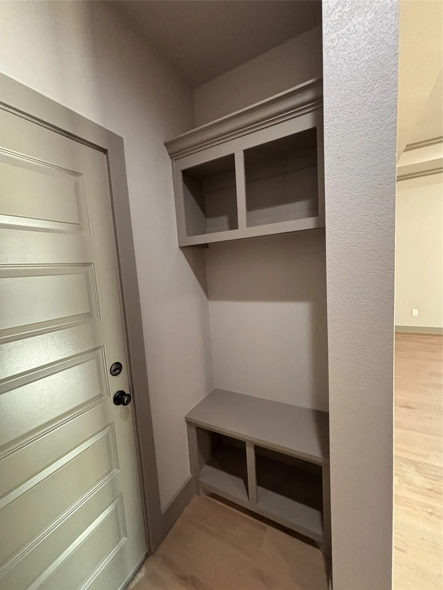 Built-in mudroom bench with cubby storage, upper open shelving, and crown molding
