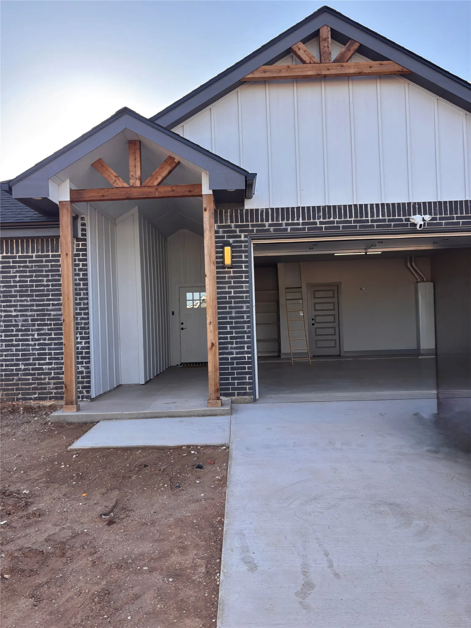 Modern farmhouse-style exterior featuring dark brick, white vertical siding, and natural wood accents