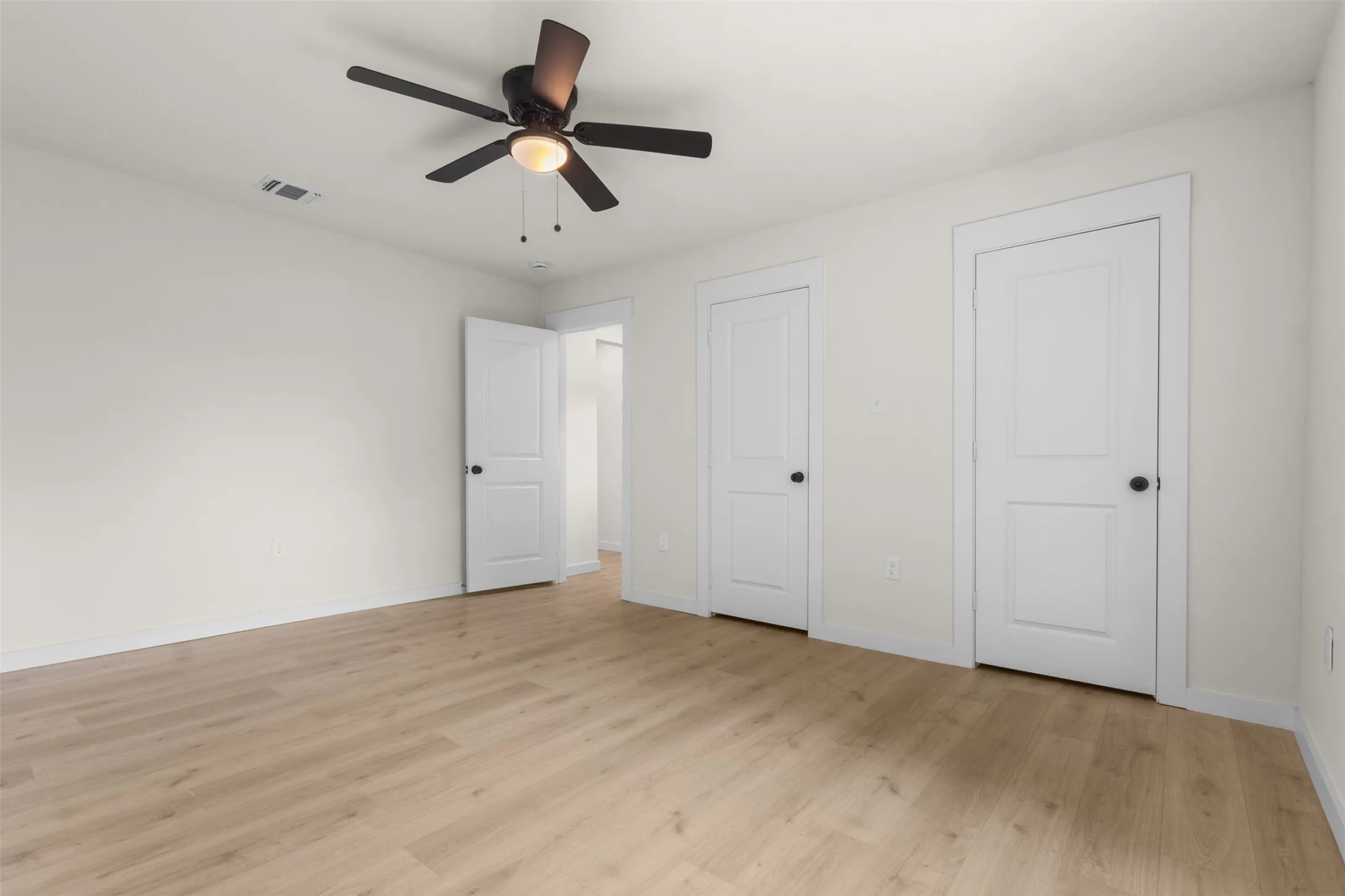 Bright interior space featuring wood-finish flooring and a ceiling fan with integrated lighting