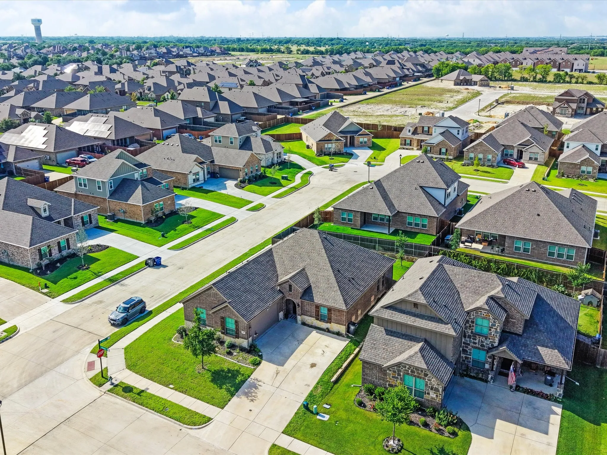 Expansive neighborhood featuring numerous residential properties with diverse architectural styles, neatly manicured lawns, and concrete streets
