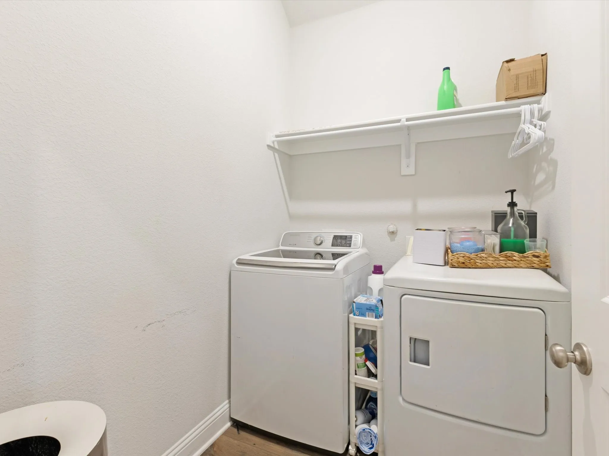 Laundry area with wood-finish flooring and white walls