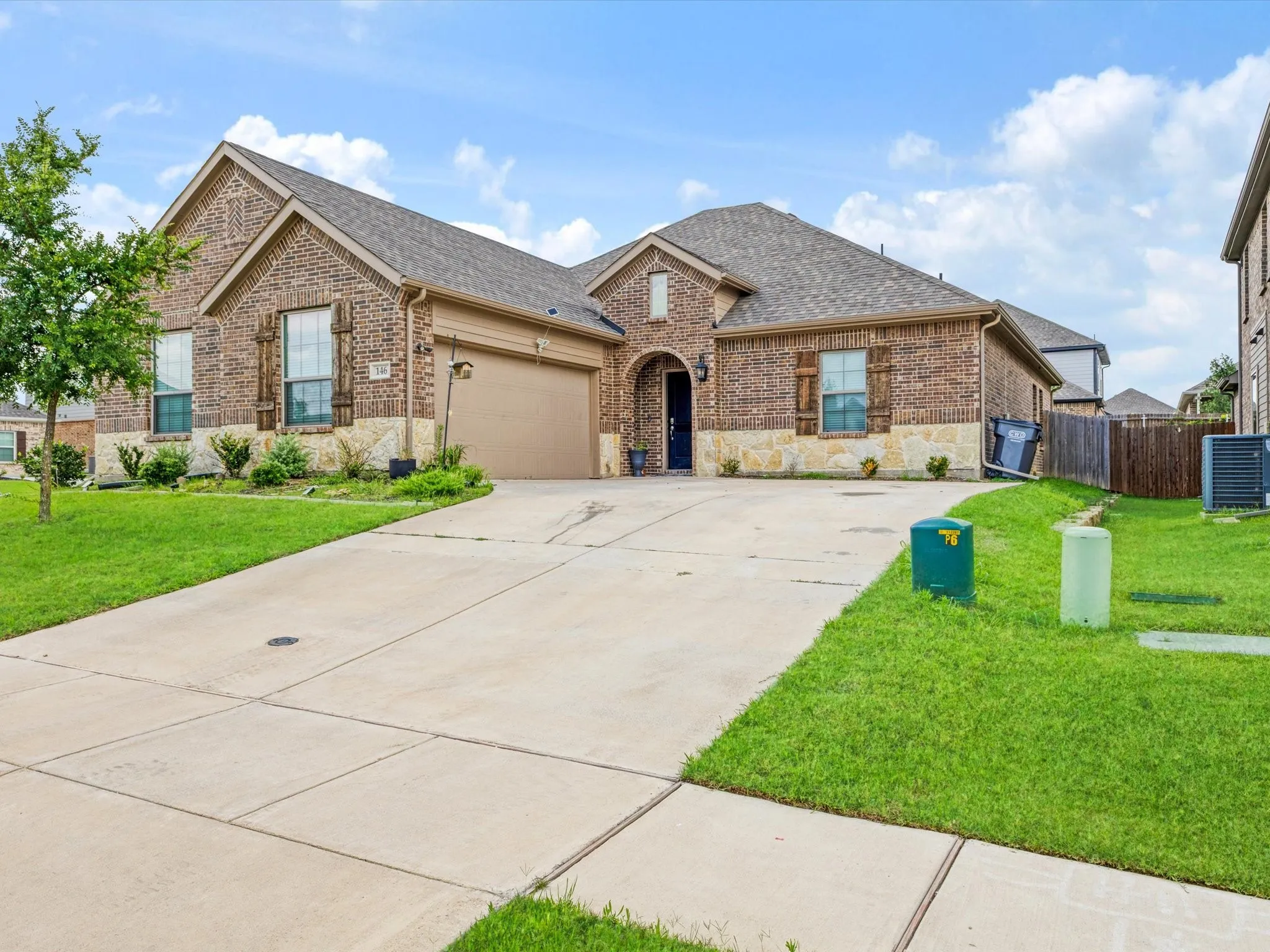 Single-story residence featuring a brick and stone facade, an arched entry, and a two-car garage