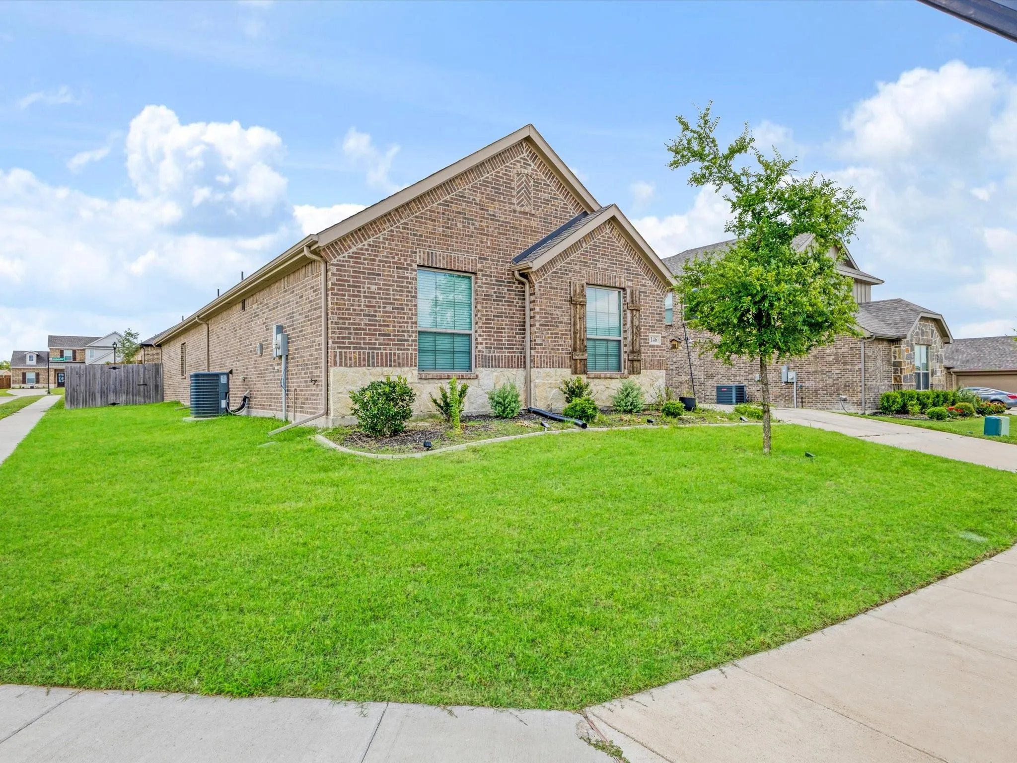 Brick exterior with a stone accent facade, featuring a well-maintained front lawn and landscaping