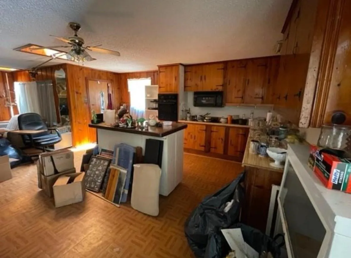 Kitchen area featuring wood-paneled walls and cabinetry, a dark countertop island, and built-in microwave
