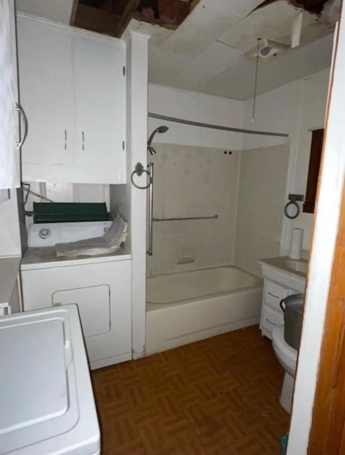 Bathroom featuring a built-in tub with shower, white vanity with sink, and pattern-tiled flooring