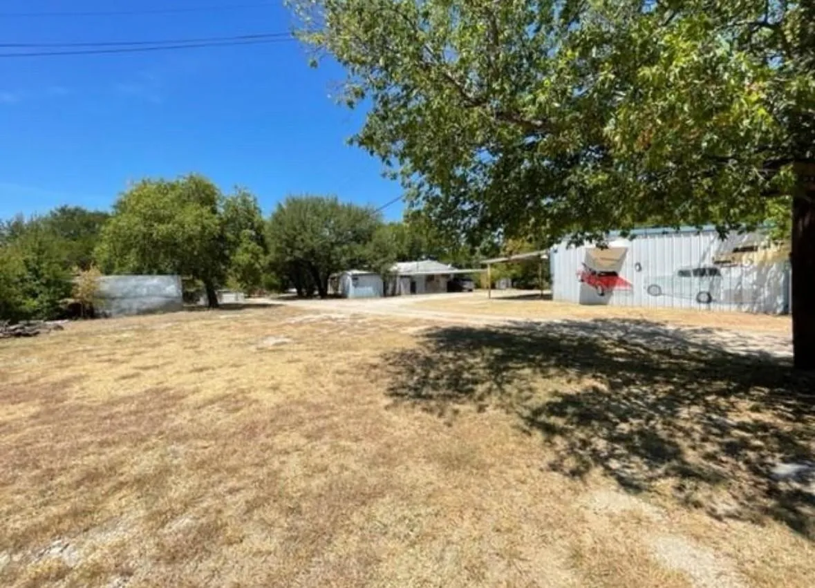 Expansive property featuring multiple outbuildings, mature trees, and a large open area