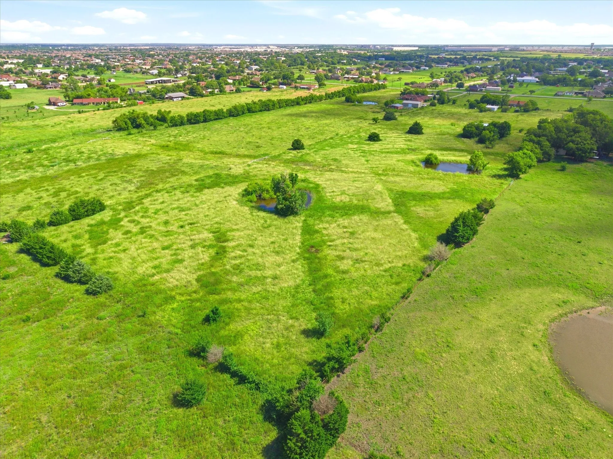 Expansive green landscape featuring varied terrain and multiple ponds