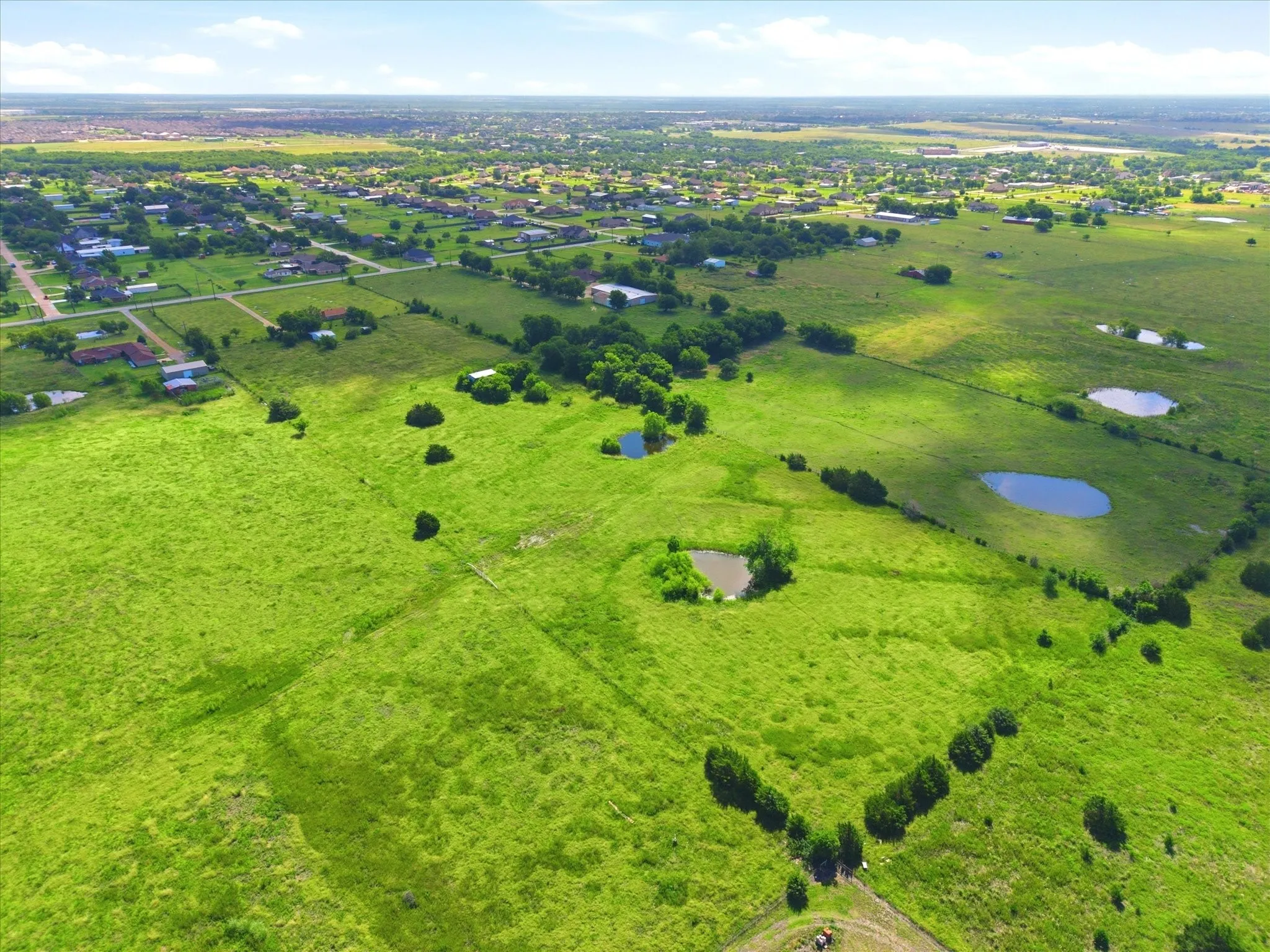 Expansive green acreage featuring multiple natural ponds and scattered mature trees
